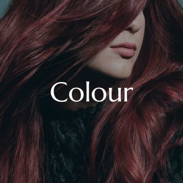 Close-up of a woman's face with long, wavy, burgundy hair covering part of her face, and the word 'Colour' written across her face.