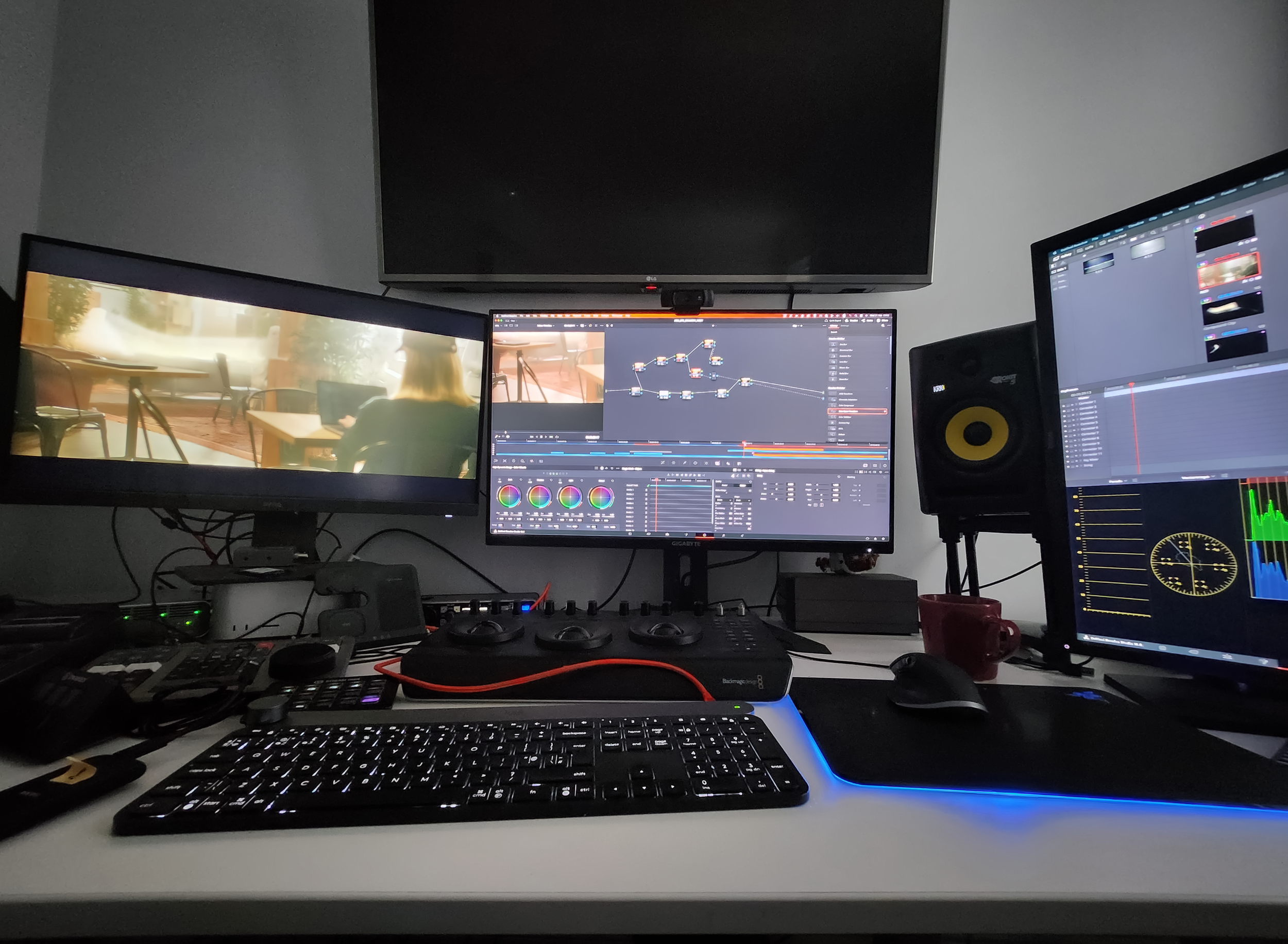 Computer desk setup with multiple monitors, audio speaker, keyboard, mouse, and various electronic devices.