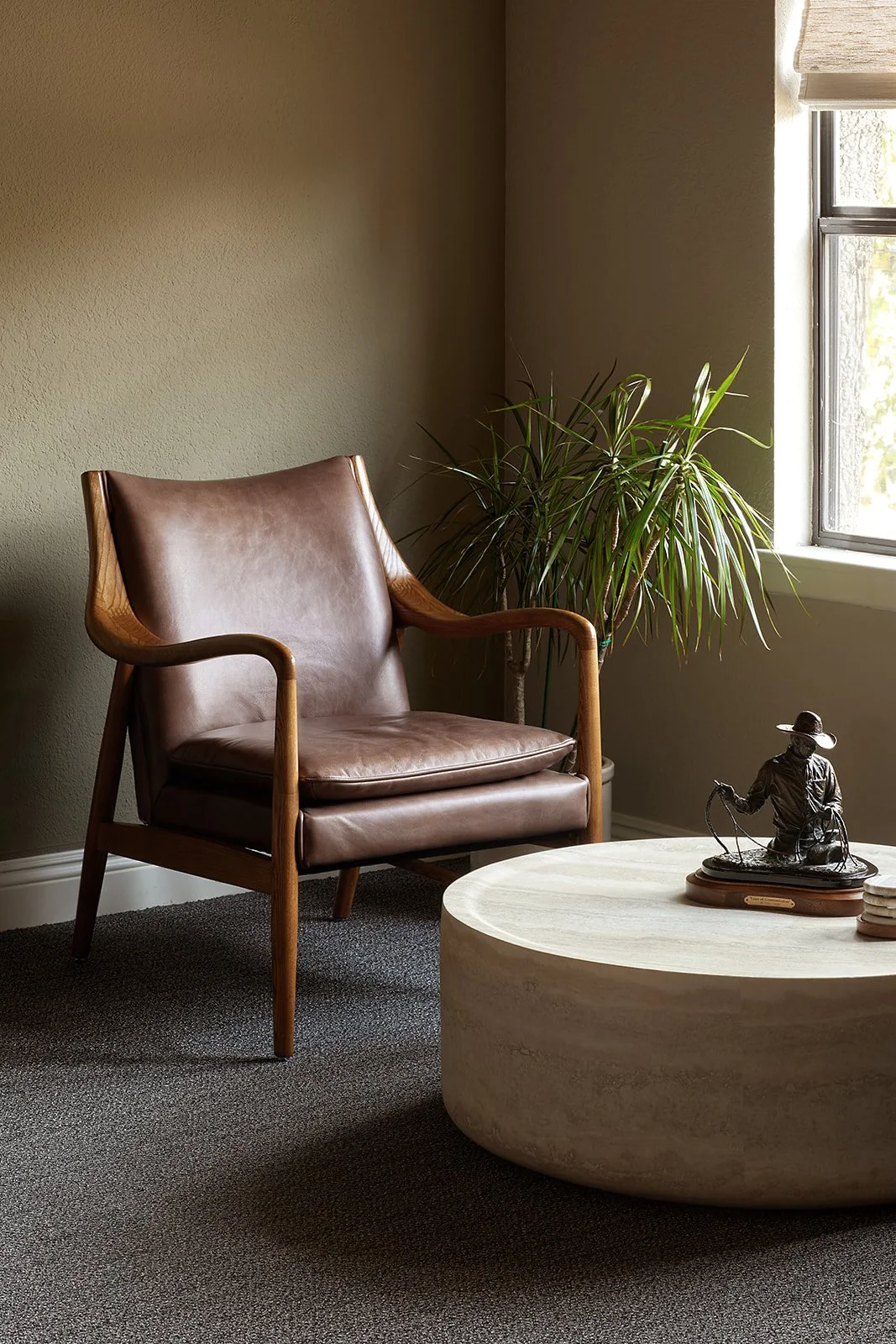 Leather armchair beside a bronze cowboy sculpture in the SYV Wealth Advisors office