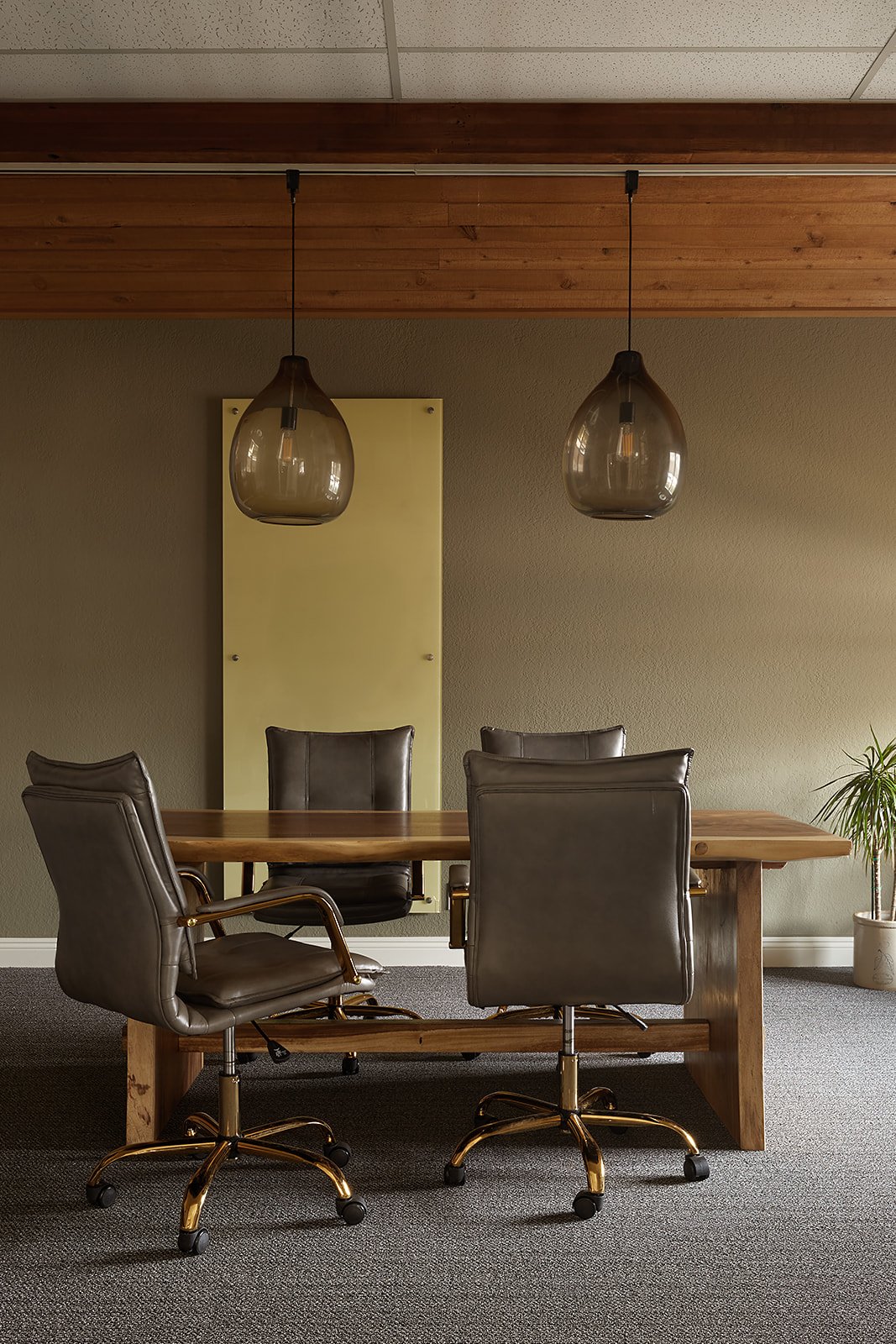 Conference room at SYV Wealth Advisors with a live-edge wood table, leather chairs, and glass pendant lights