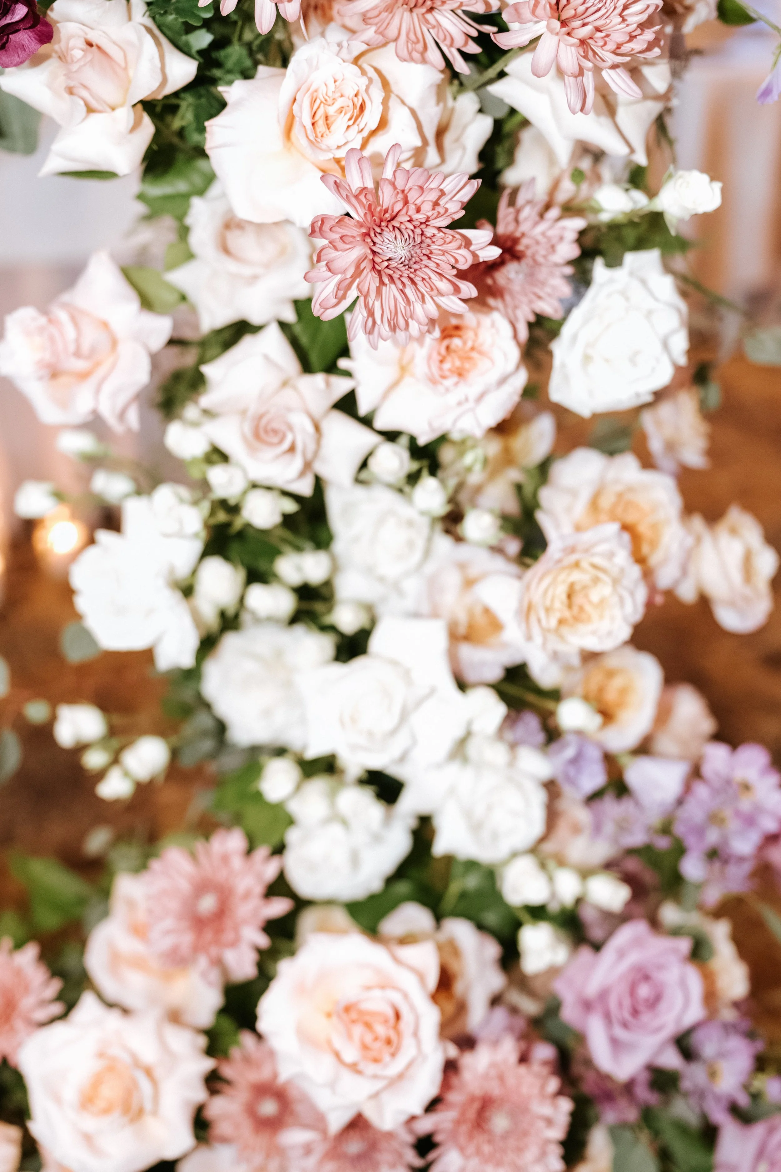 A beautiful floral arrangement featuring pink gerbera daisies, white roses, and peach-colored roses.