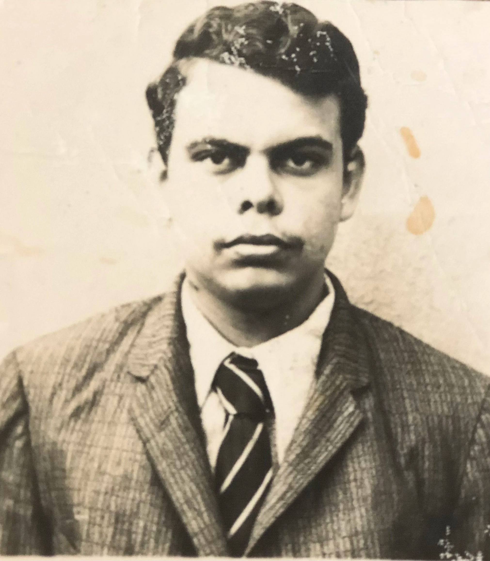 A black and white portrait of a young boy in formal clothing, wearing a suit jacket, a collared shirt, and a striped tie.