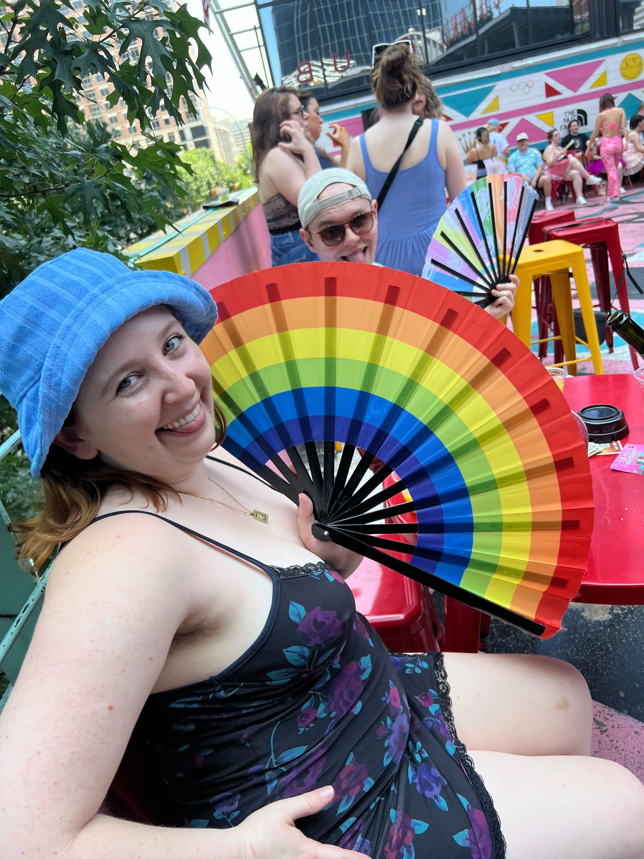 A picture of Social Media Consultant Clair Daly in a blue bucket hat and showing her rainbow rave fan