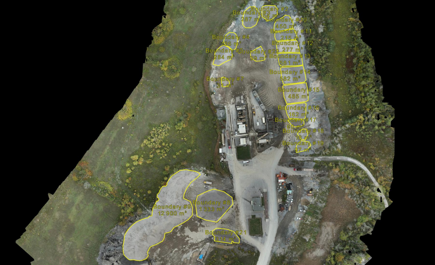 Construction site with building covered in Tyvek HomeWrap, a partially excavated area marked in red, measurements, and construction materials and tools on the ground.