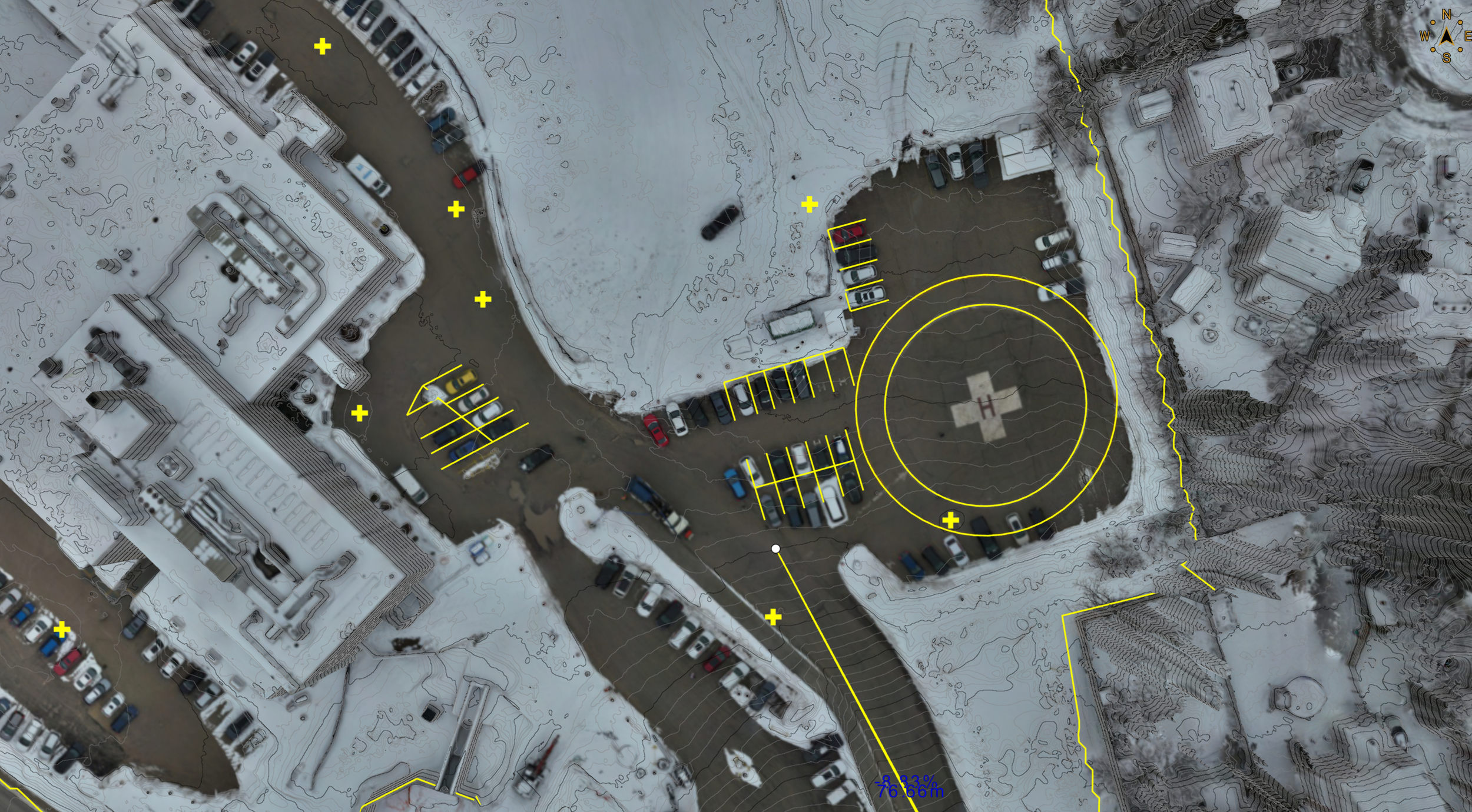 Aerial view of a construction site adjacent to a residential building and a green lawn.