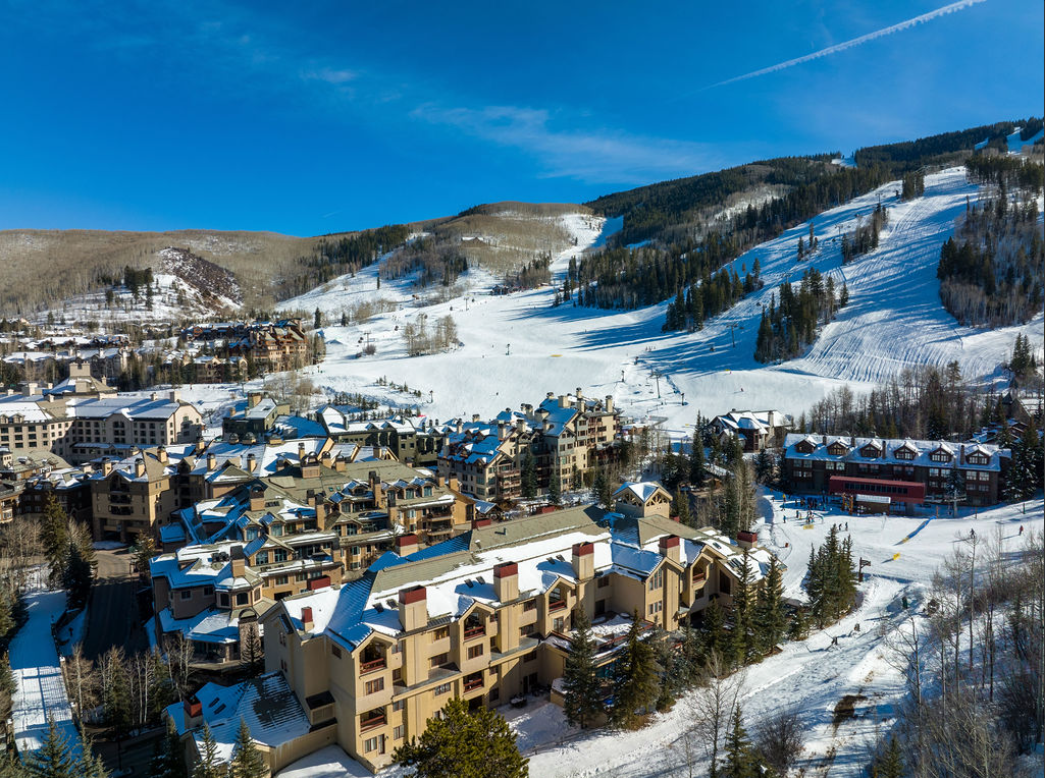 Snow-covered buildings and ski slopes on a mountain under a blue sky