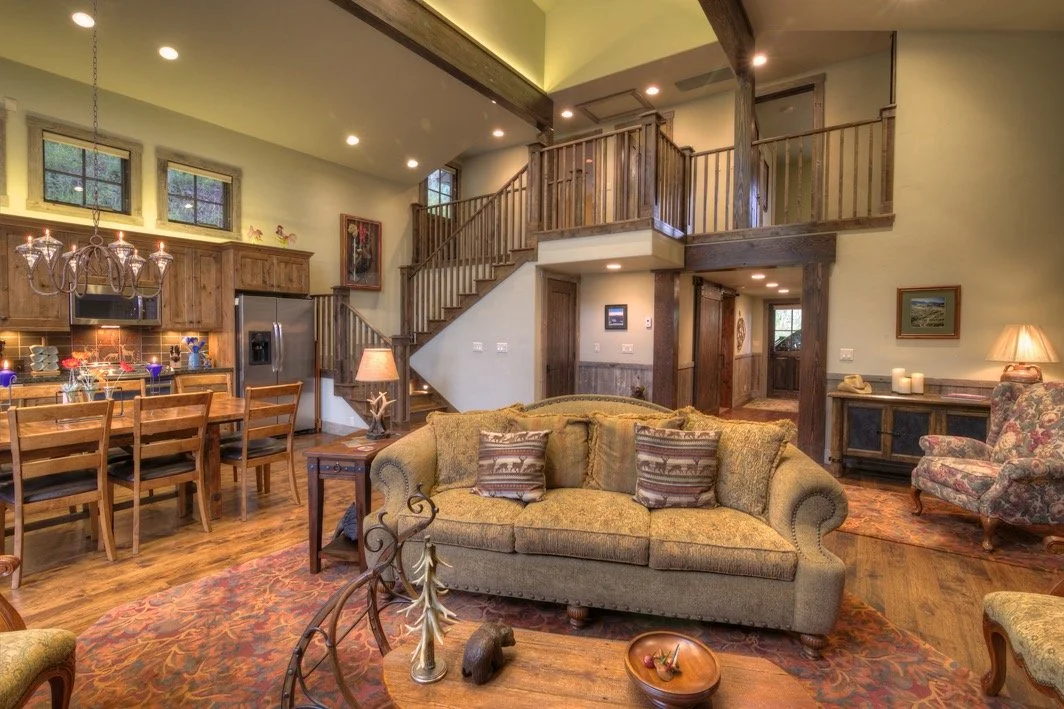 Open-concept living room and kitchen with wooden accents, staircase, and seating area.