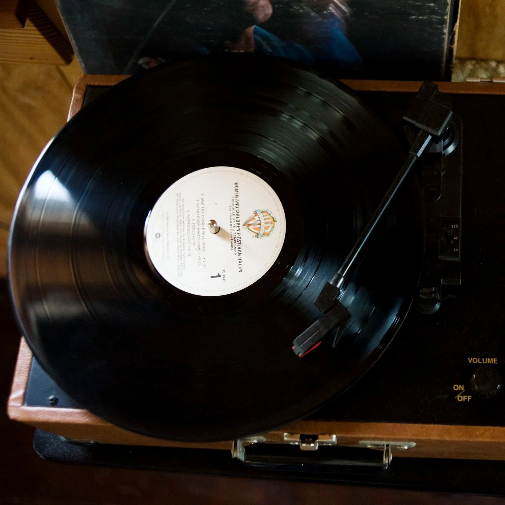 A vinyl record spinning on a turntable with a wooden base and a black tonearm.