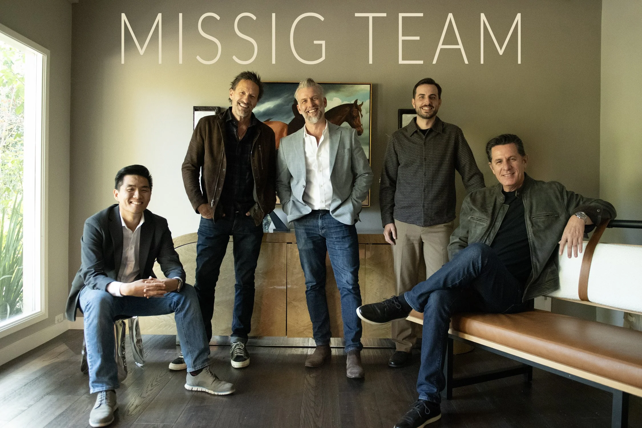Group of five men smiling, standing and sitting in a room with a picture of a horse on the wall and the words 'MISSIG TEAM' written above them.