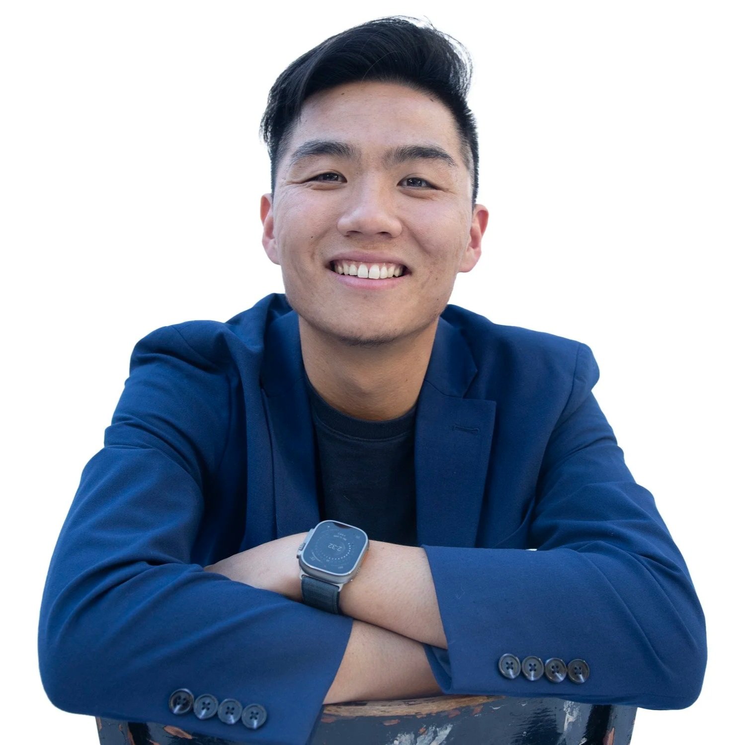 Leo Li, wearing a navy blue jacket and a black watch, sitting with his arms crossed and leaning on a surface, against a plain white background.