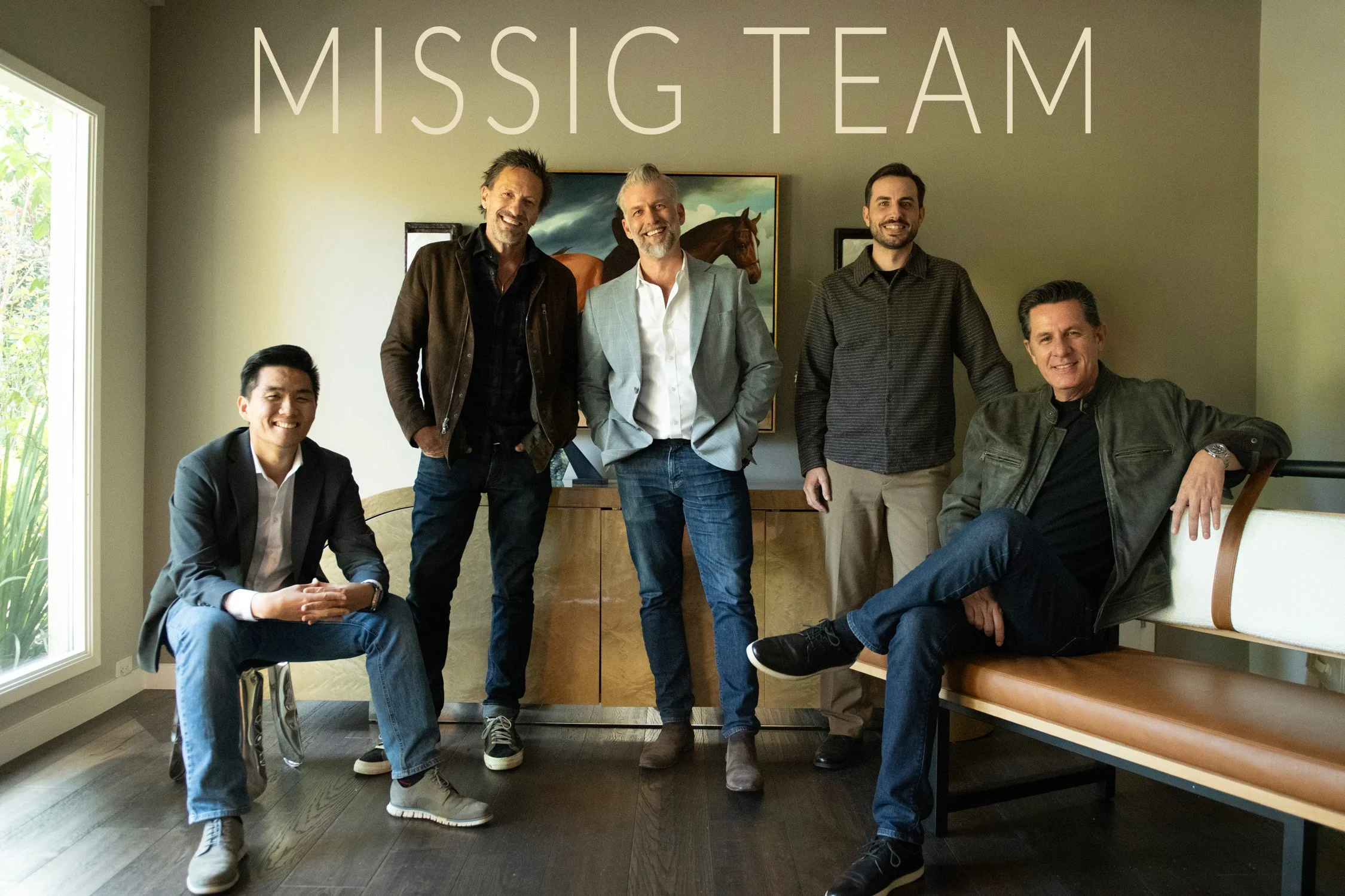 Five men posing together in a room with a large window, a painting of horses, and the words 'MISSIG TEAM' written above them.