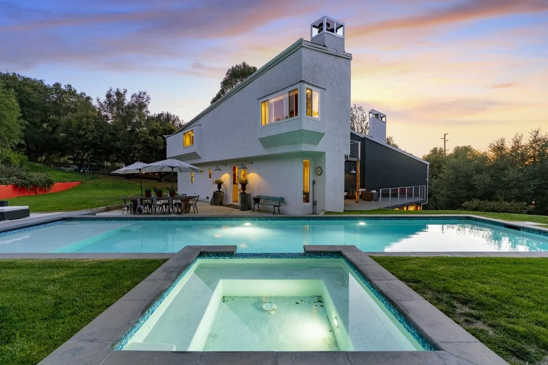 Presented by Missig Team, a real estate team at Berkshire Hathaway HomeServices California Properties in Beverly Hills and Los Angeles. Modern house with outdoor pool and hot tub at sunset