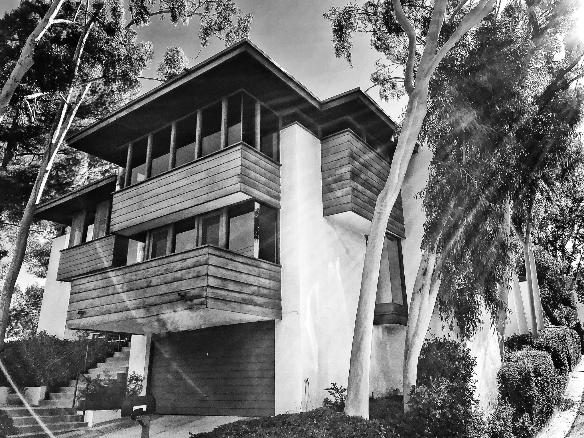 The Spanner Residence, a 1968 mid-century architectural home in the hills designed by Rex Lotery FAIA. Features interlocking volumes, mitered corner windows, high clerestories, patios, pool, and lush plantings. Includes 3 bedrooms, ground-floor libra