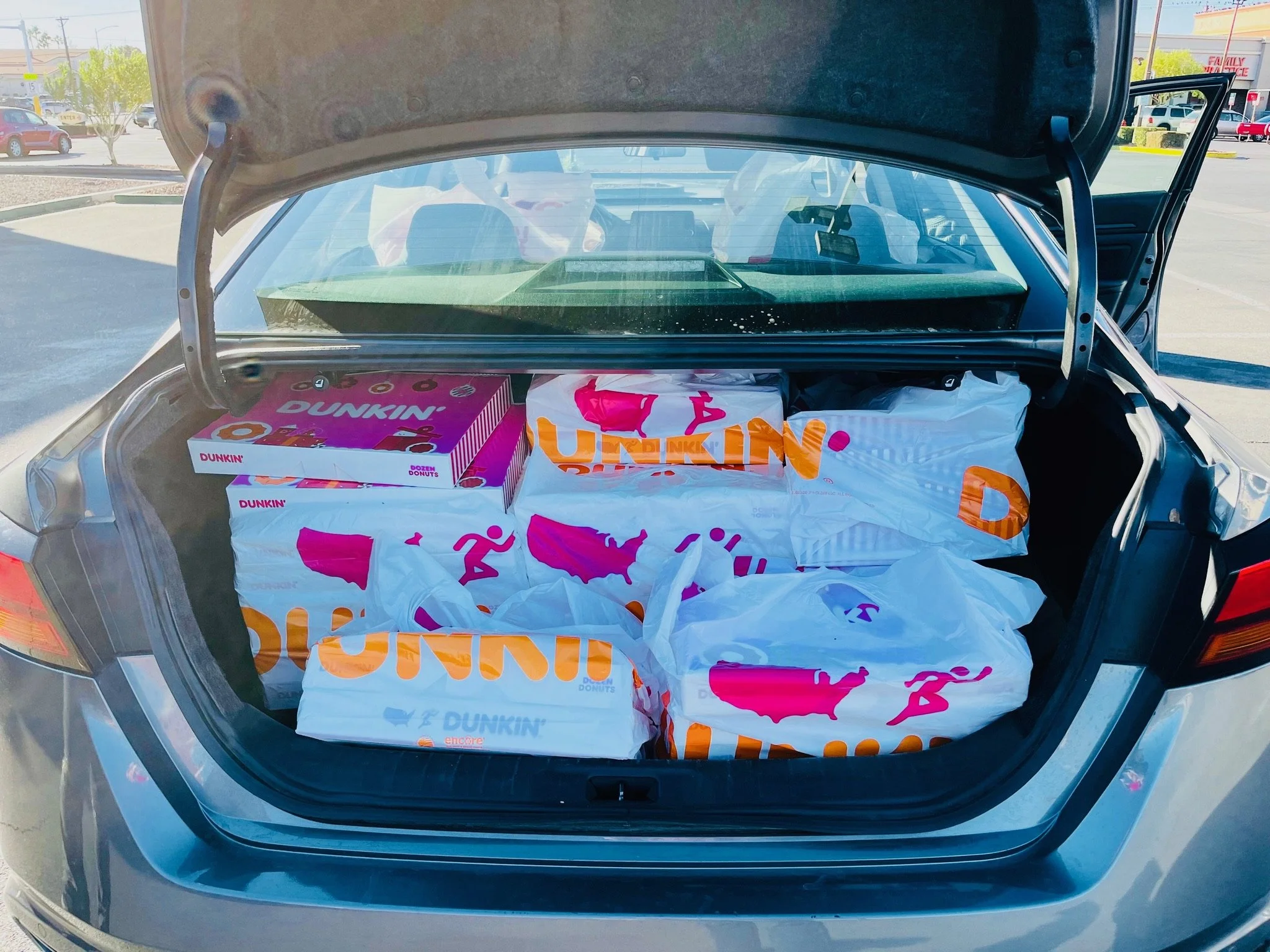 Car trunk full of Dunkin Donuts boxes.