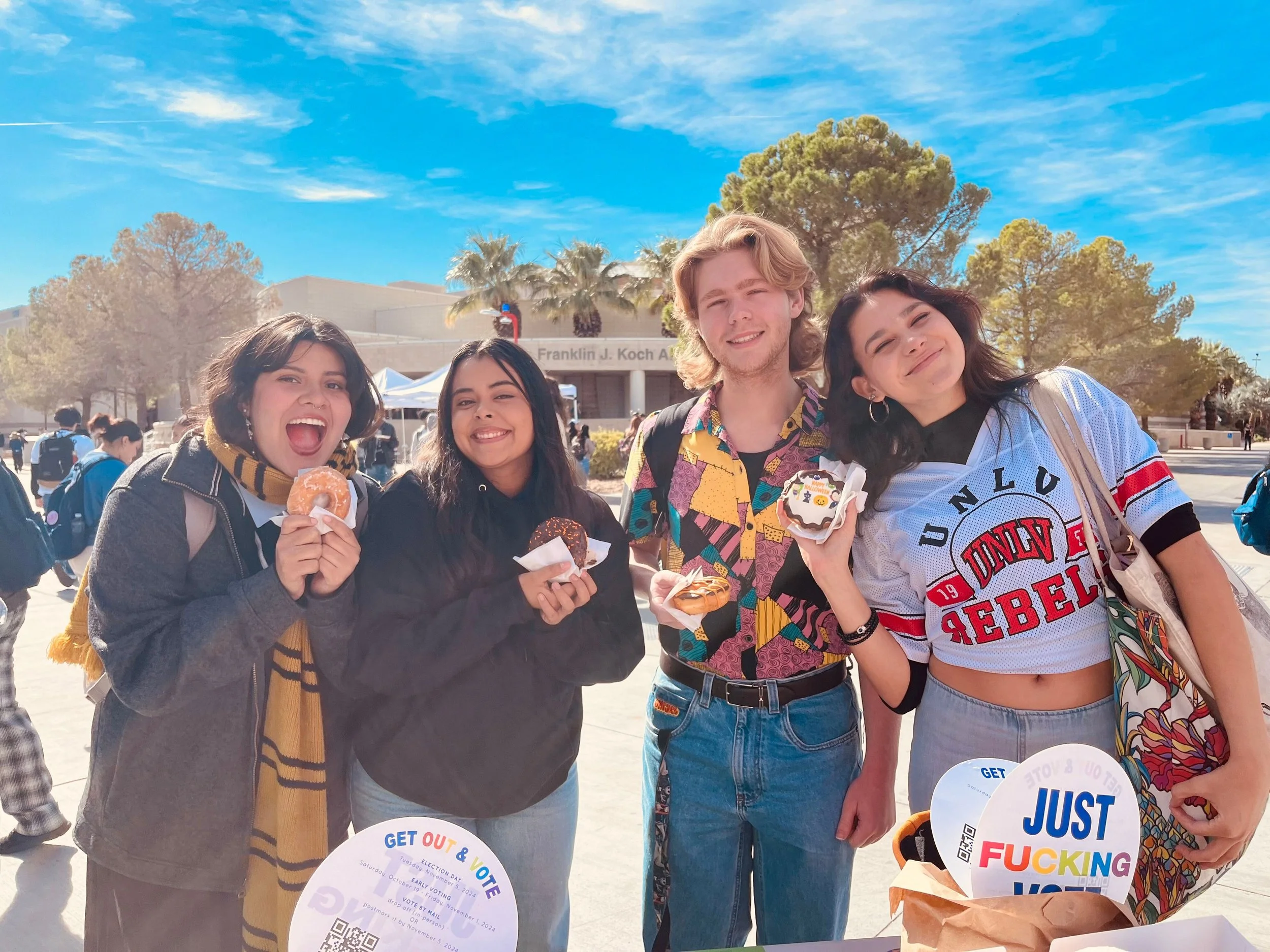 College students with donuts and Just Fucking Vote signs at Donuts and Democracy table.