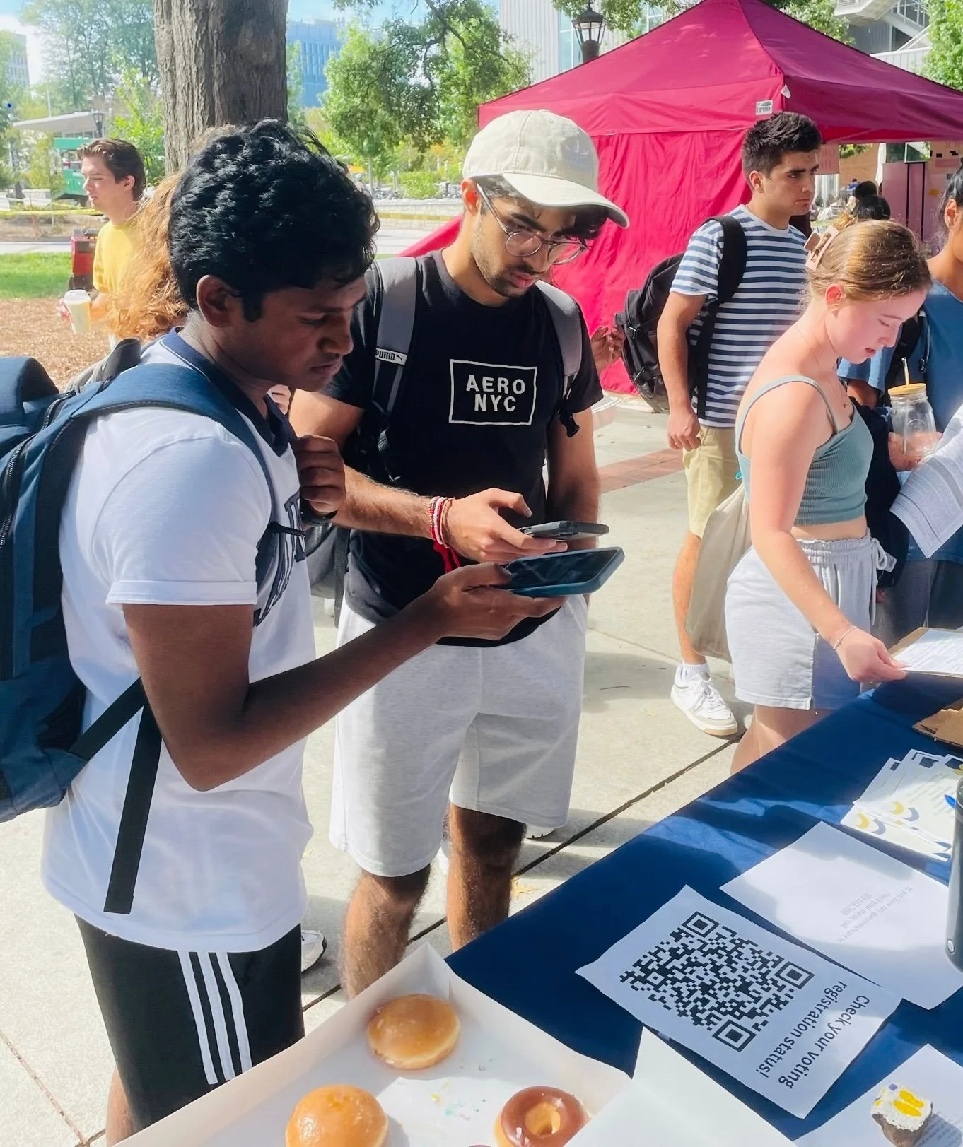 College students checking voter registration at Donuts and Democracy table.