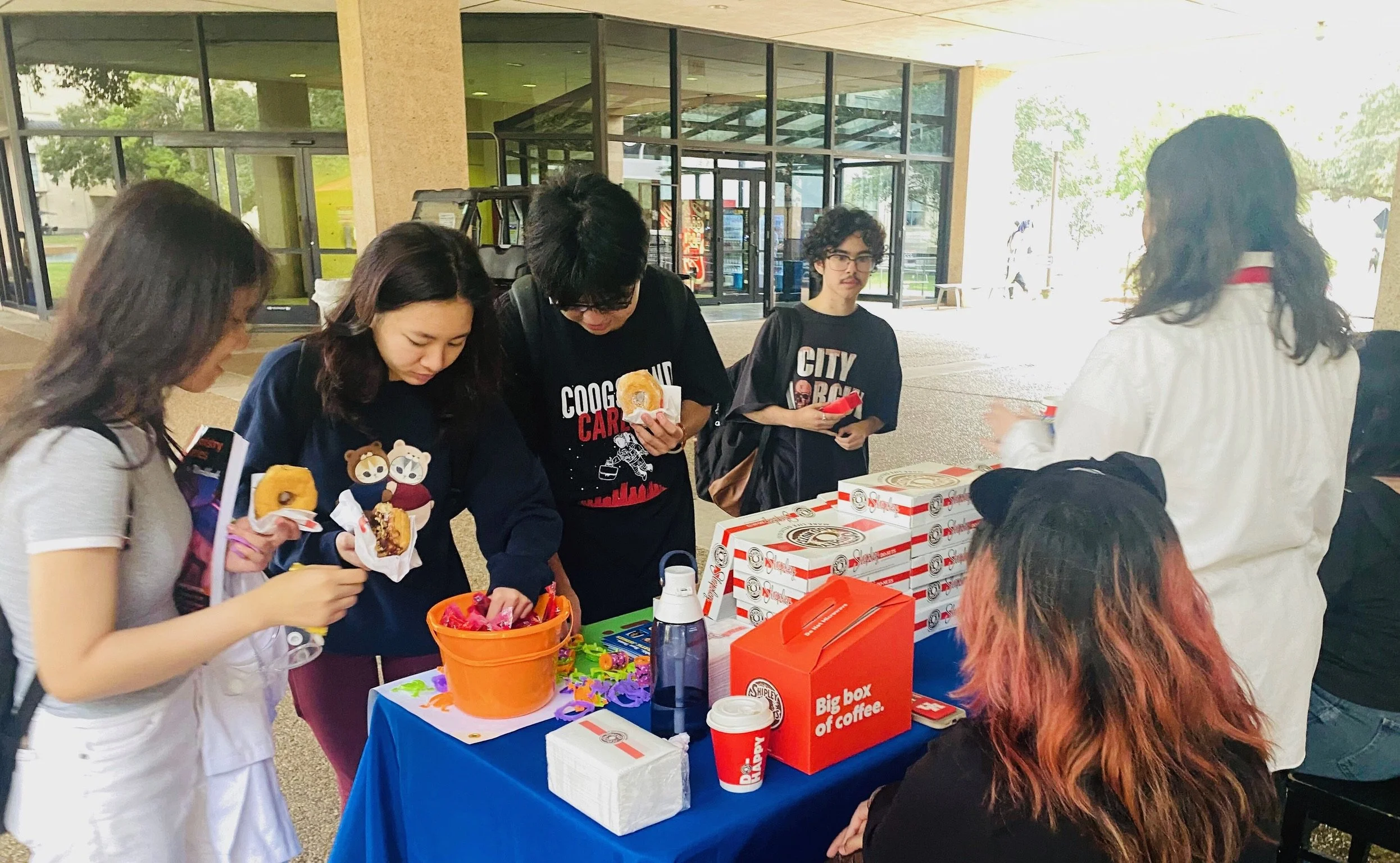 College students checking voter registration at Donuts and Democracy table.