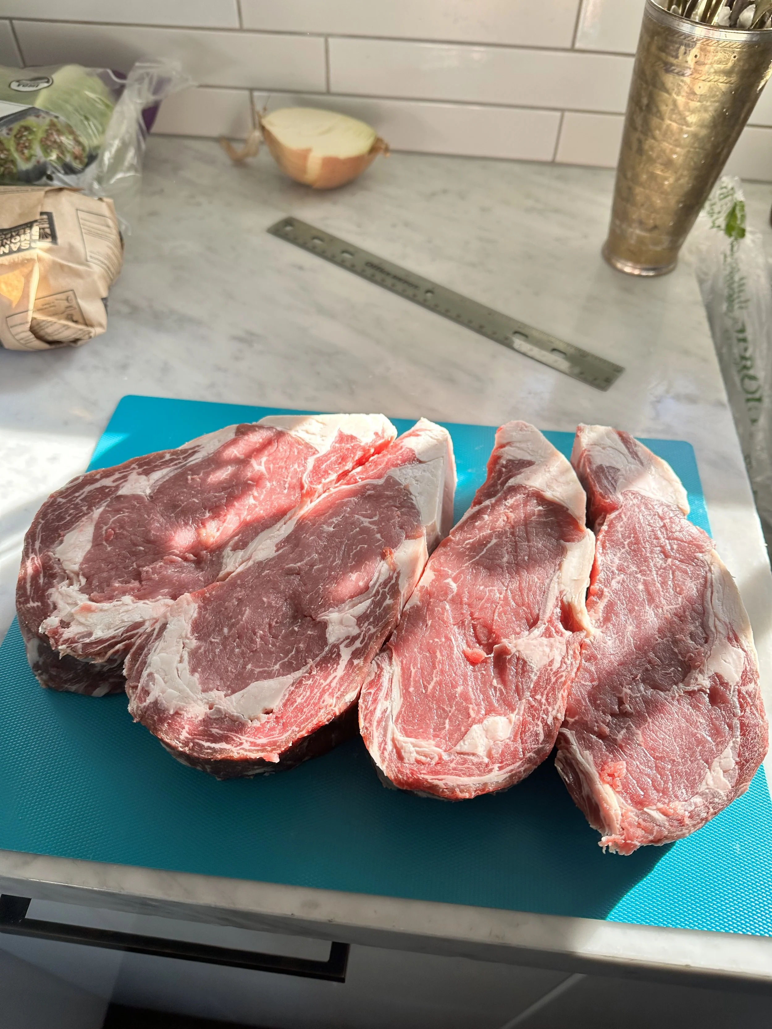 Four large raw pork chops on a blue cutting board in a kitchen.