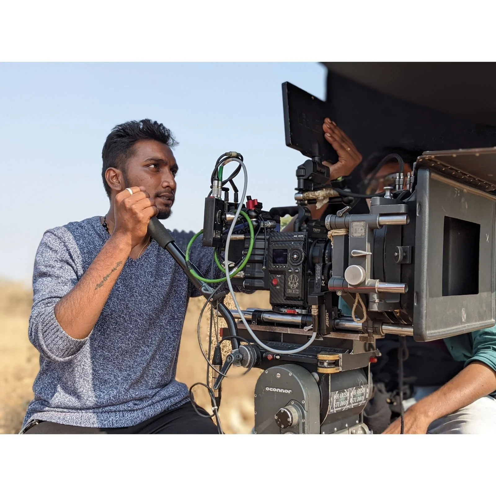 A man operating a professional movie camera outdoors.