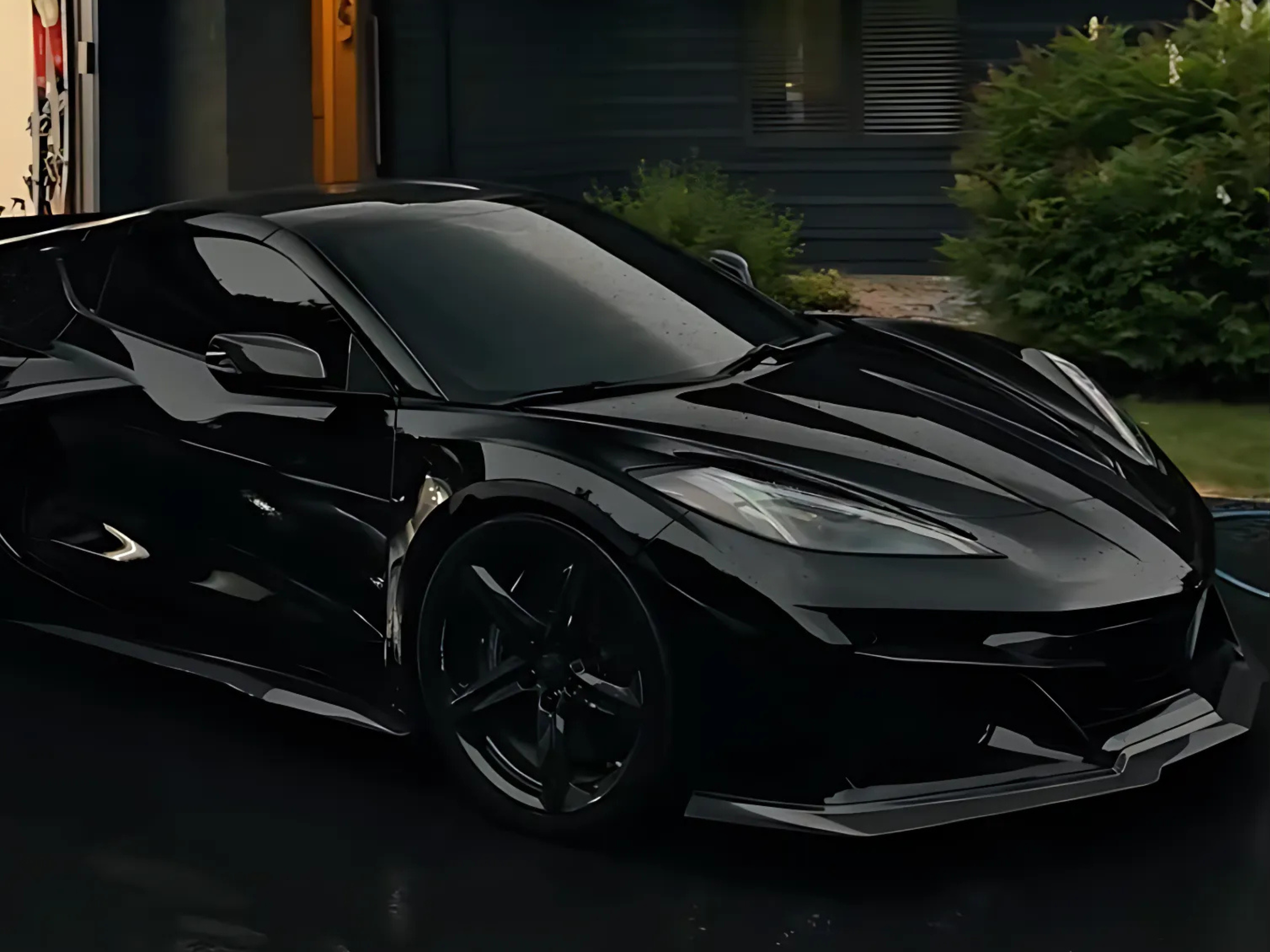 Black sports car parked outside near greenery with dark-colored building in background