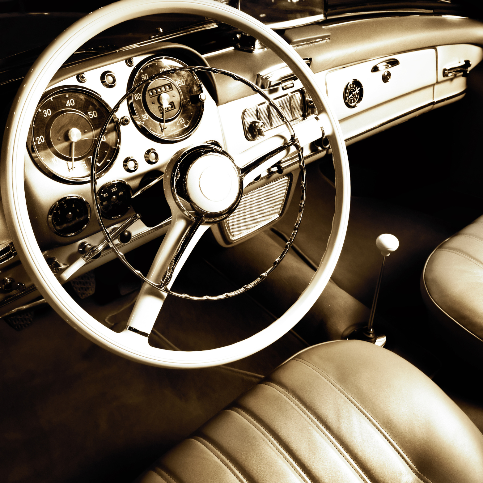 Interior of a vintage car with a cream-colored steering wheel, dashboard, and front seat.