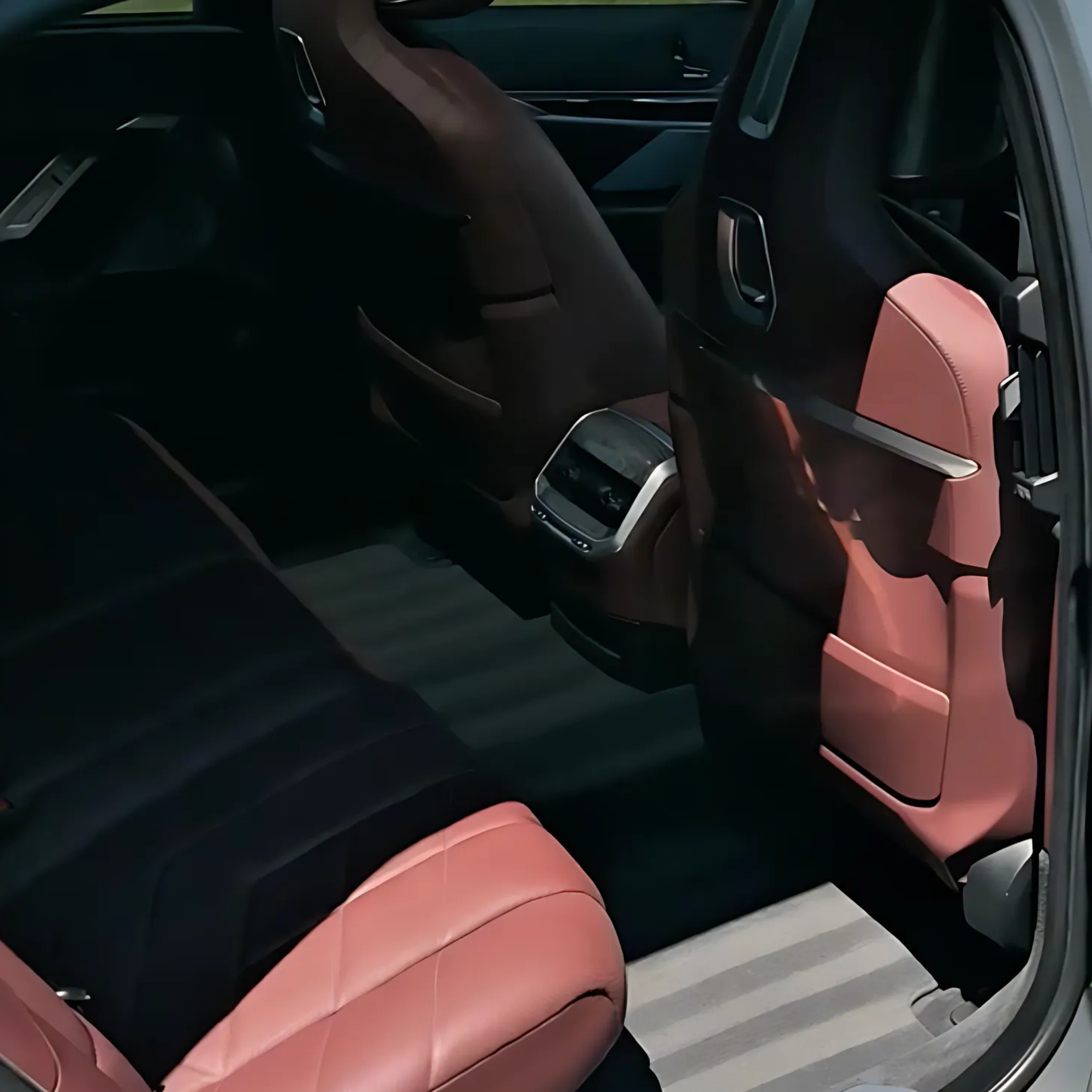 Interior of a car showing the back seats and front seats, with pink seat accents and dark upholstery.