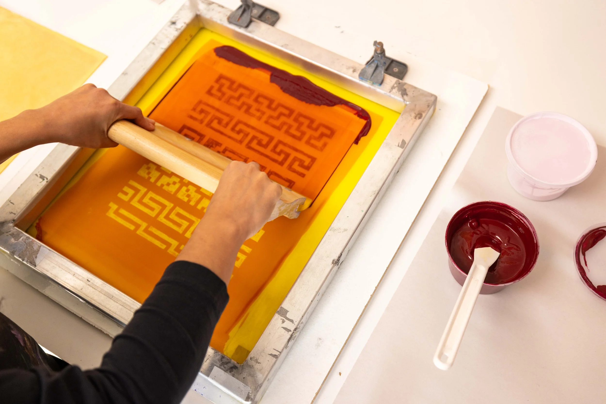 A person pulling down ink on a screen print.