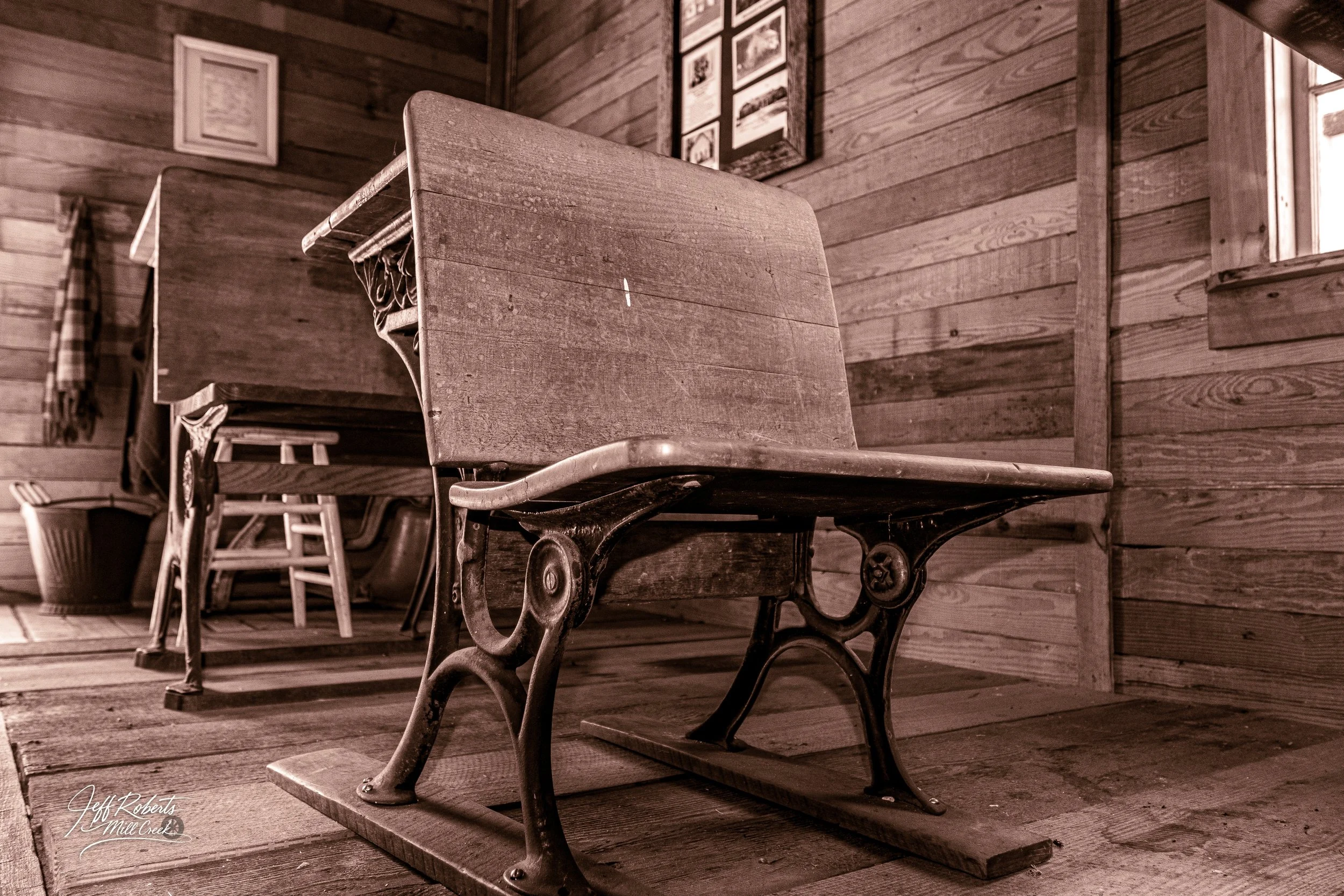 Vintage wooden and metal school desk in a rustic wooden room.