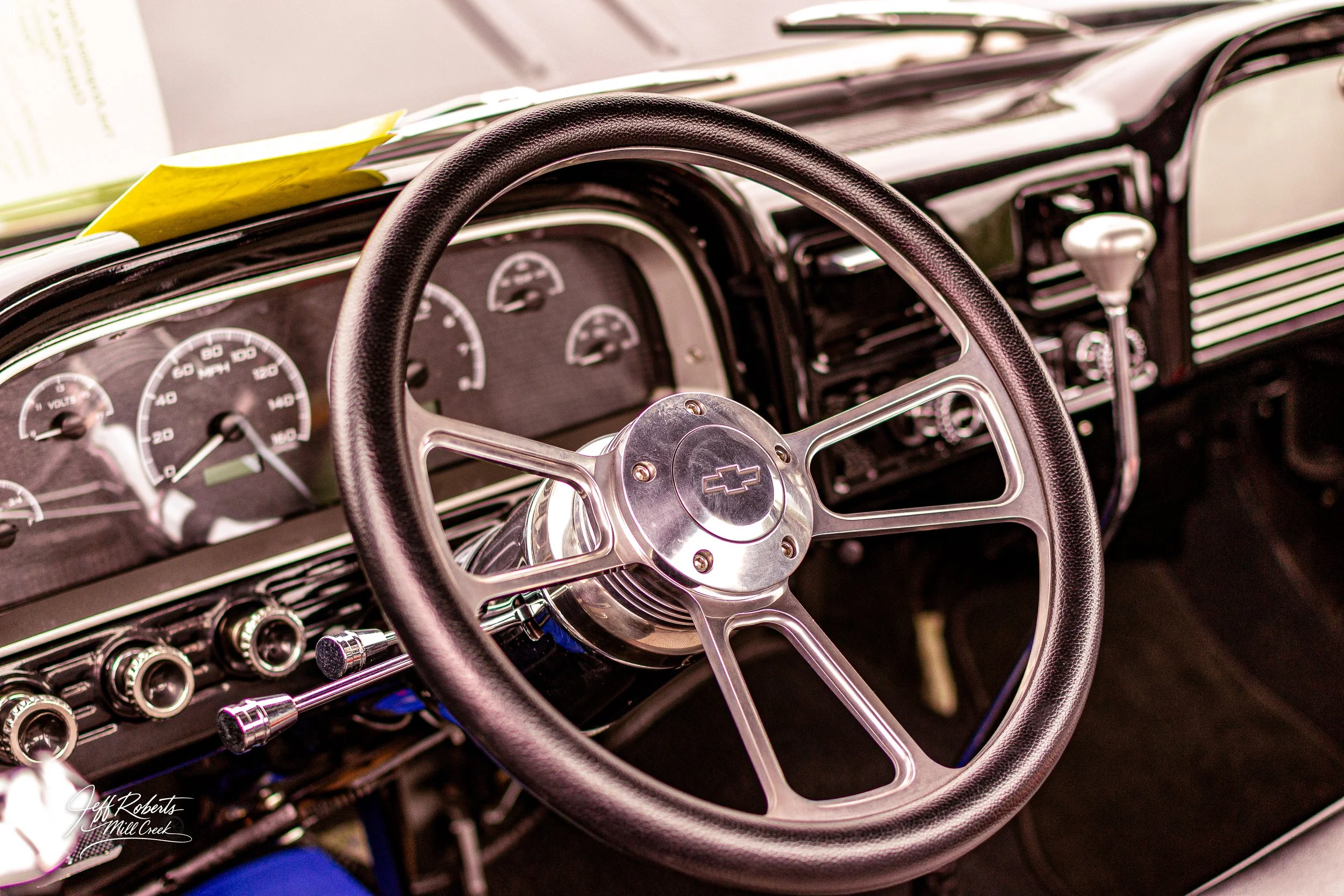 Close-up of the interior of a vintage Chevrolet car, showing the steering wheel, dashboard with gauges, and gear shifter.