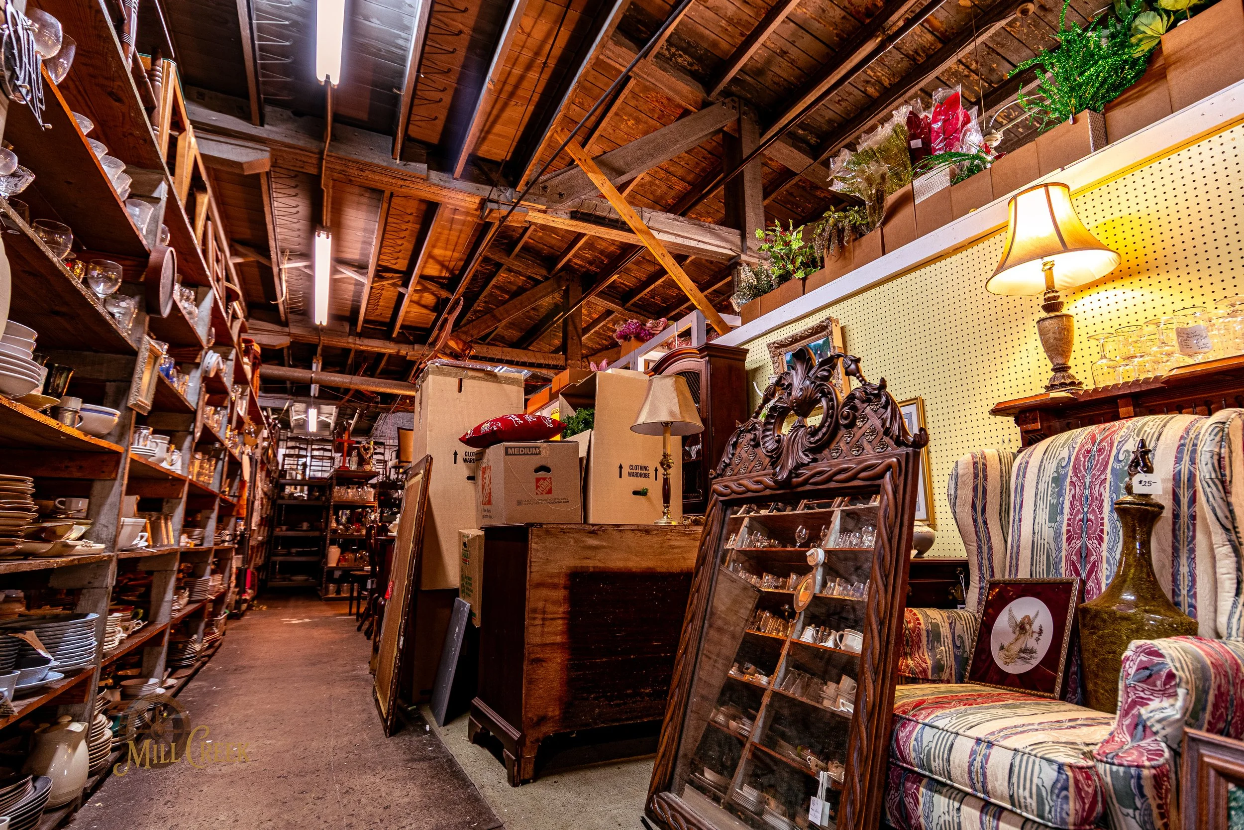 Interior of an antique store with shelves filled with dishes, lamps, and furniture.