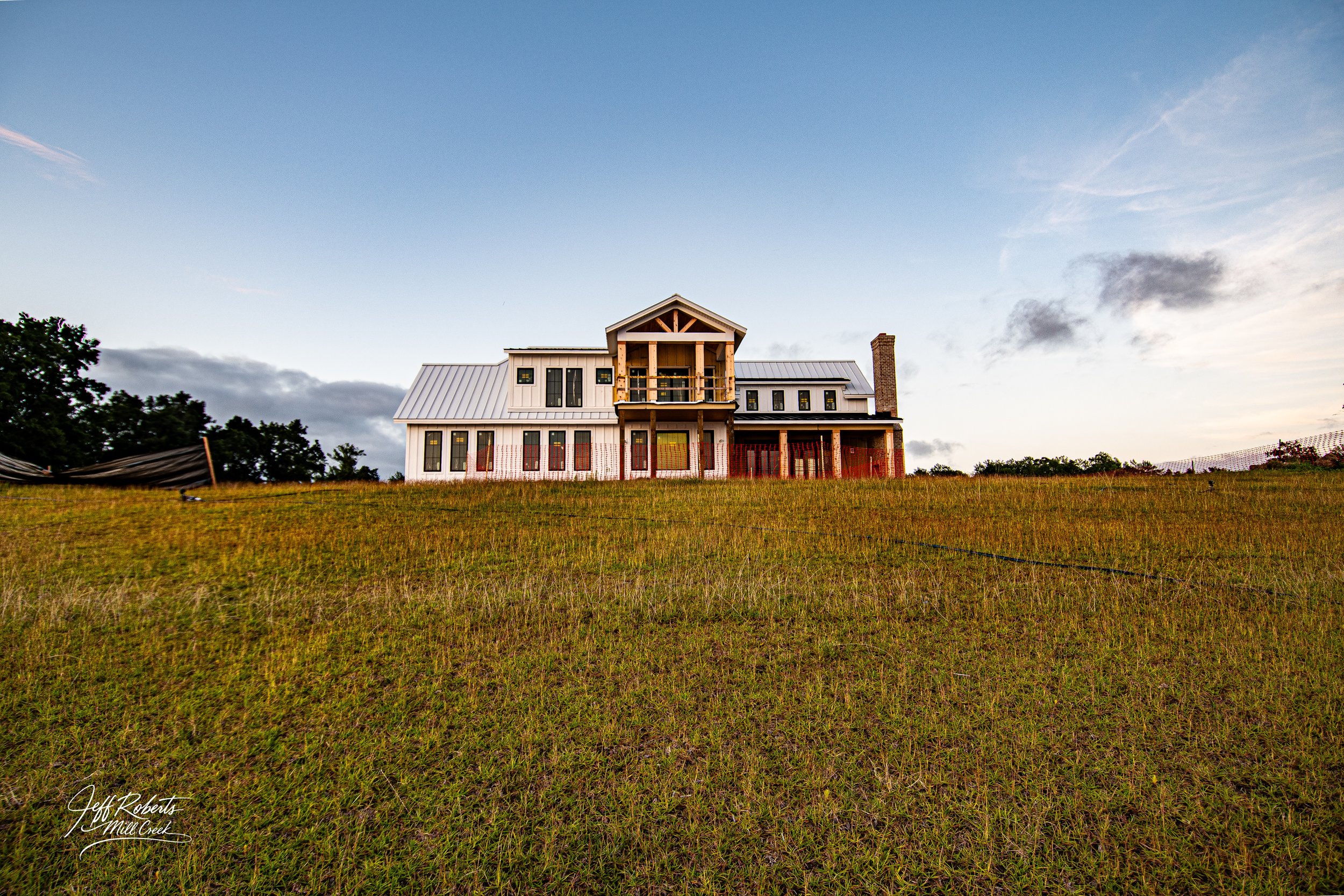 Newly constructed house on a grassy hill with a partly cloudy sky in the background.