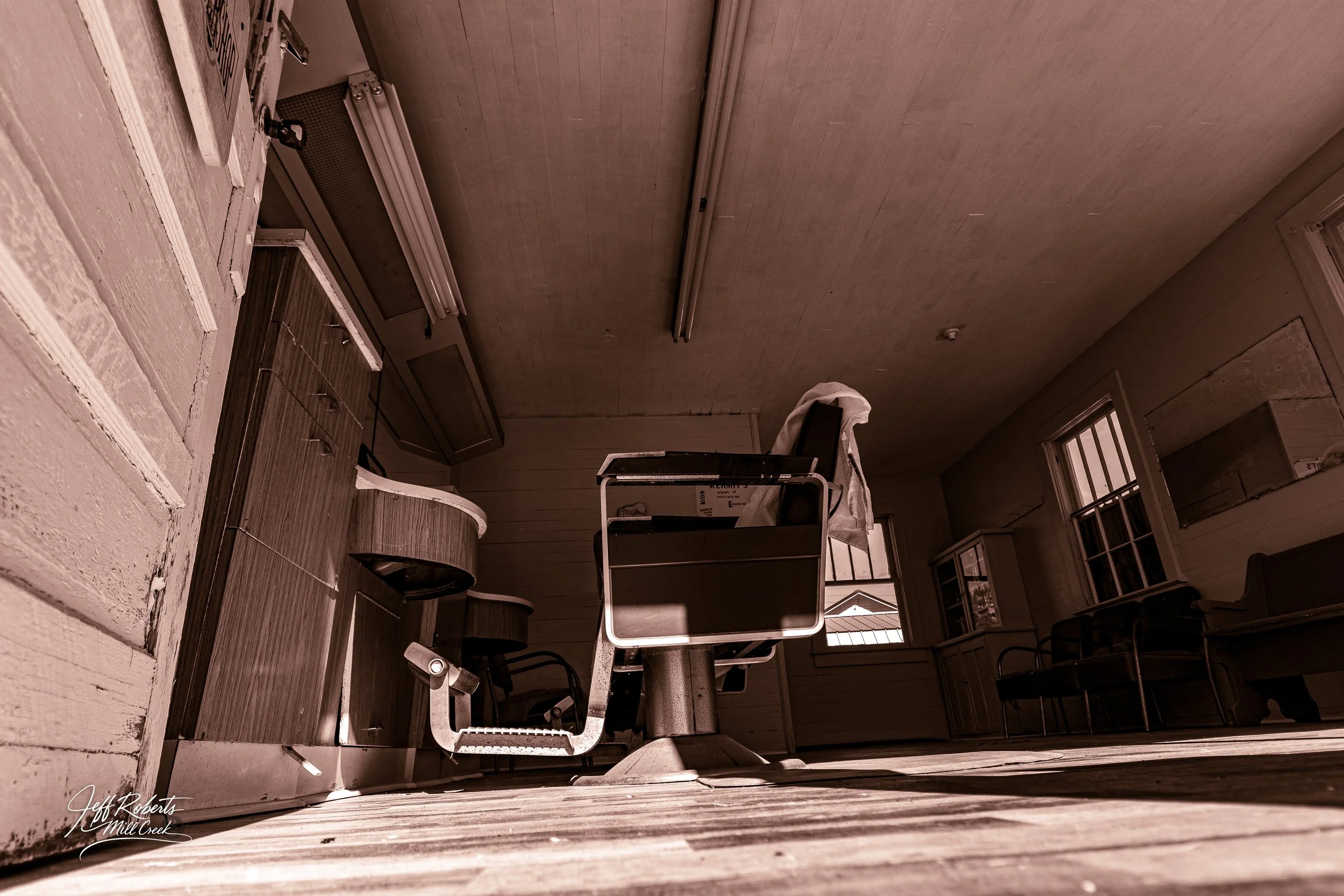 An empty vintage barber chair in an old-fashioned barber shop with wooden floors and vintage furniture.