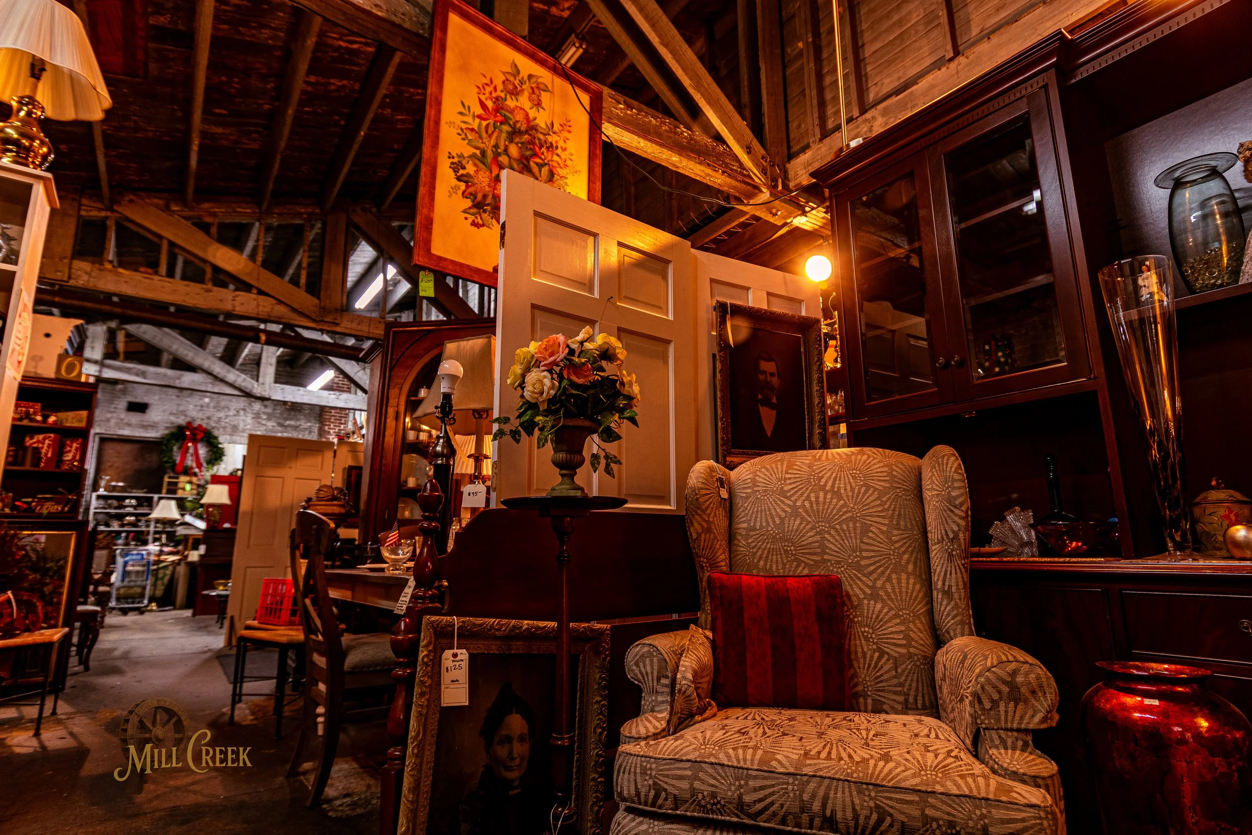 Interior of a vintage store with antique furniture, artwork, and decorative items in warm lighting.