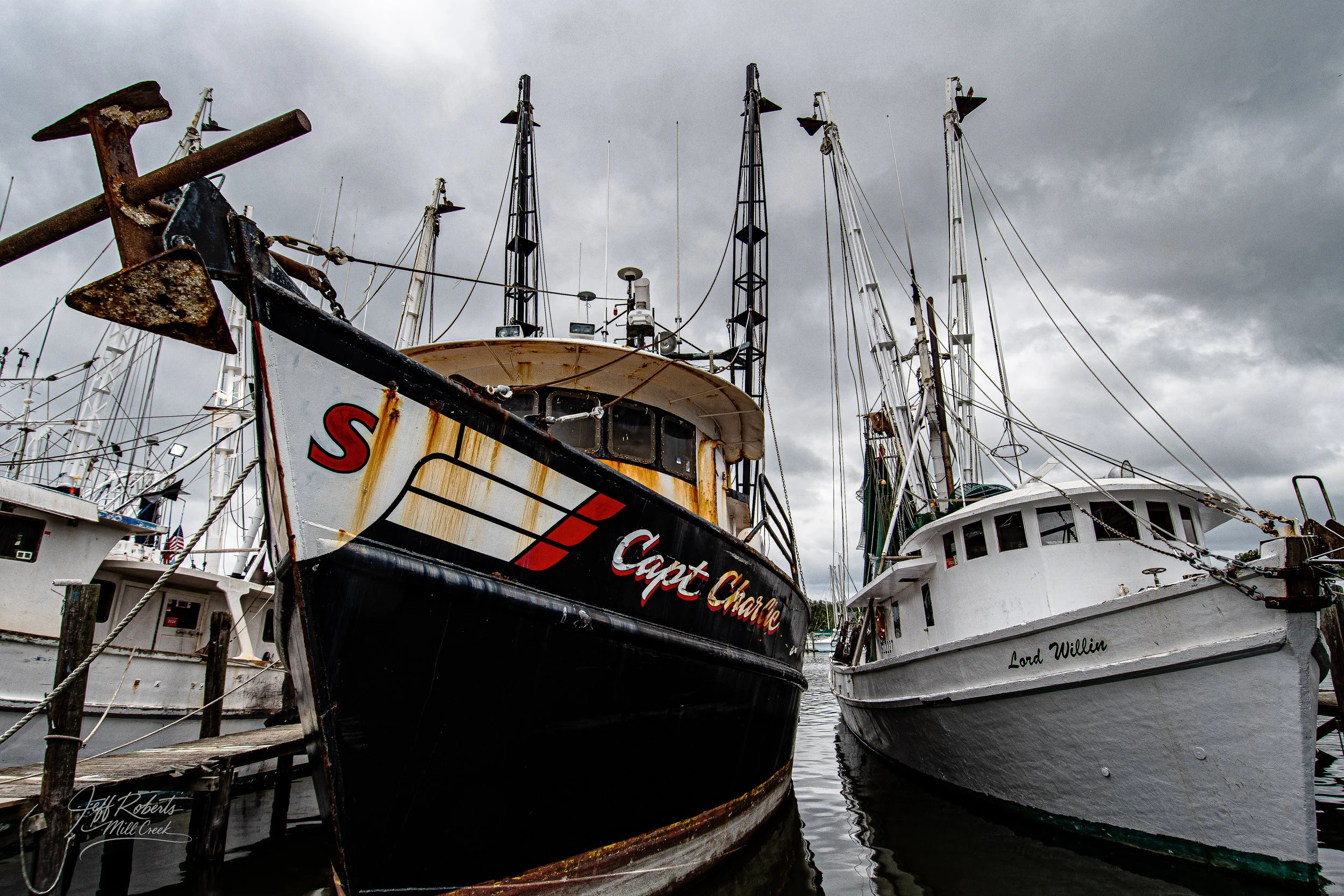 Two fishing boats docked at a marina with cloudy sky.