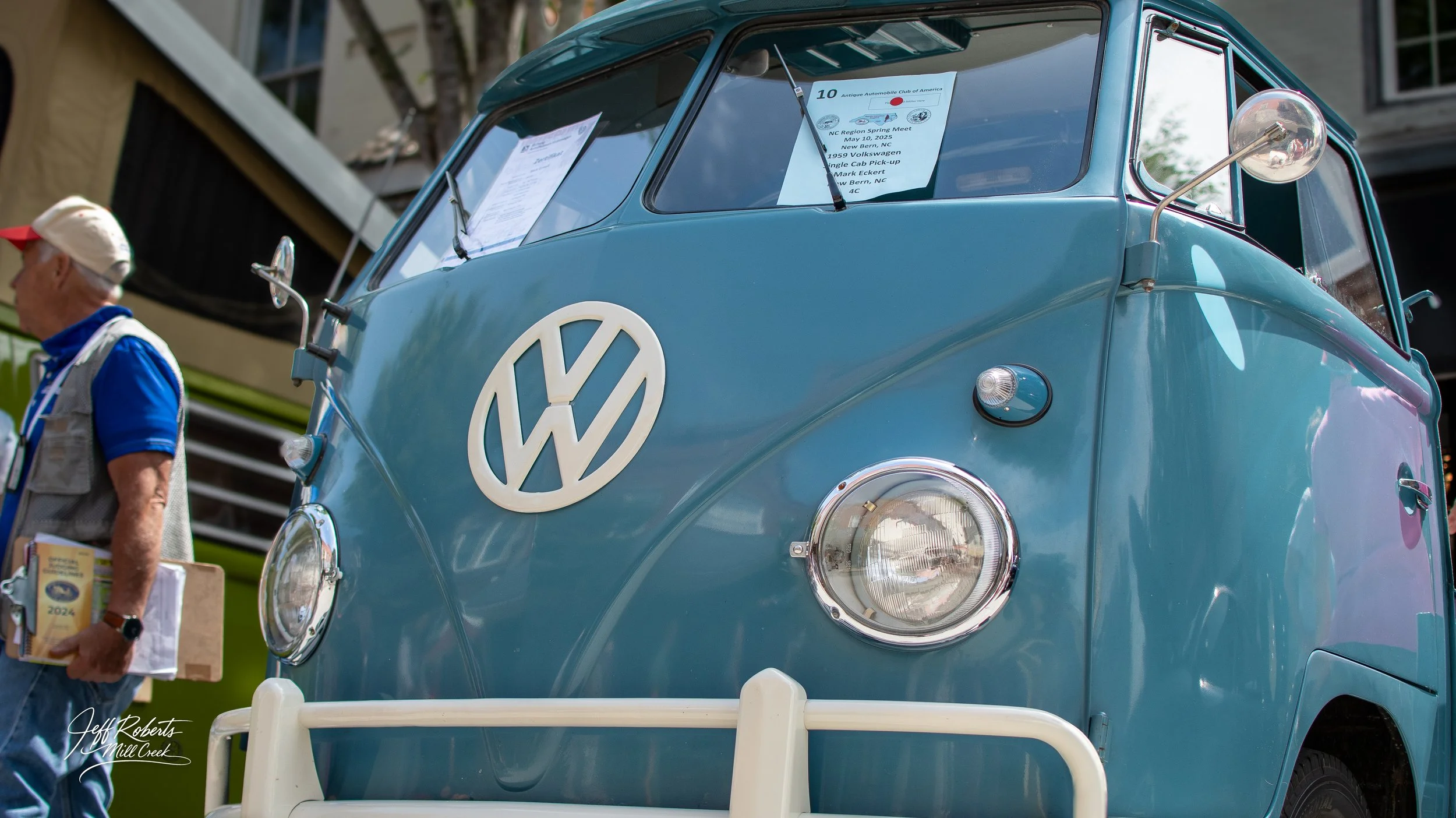 A vintage blue Volkswagen Type 2 (microbus) shows the front view at a Car Show.