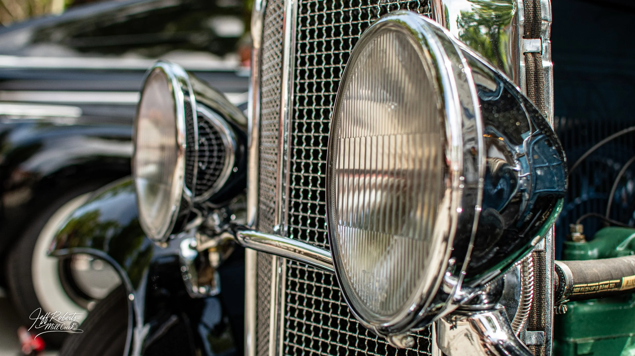 Close-up of the front grille and headlights of a vintage black car with chrome details.