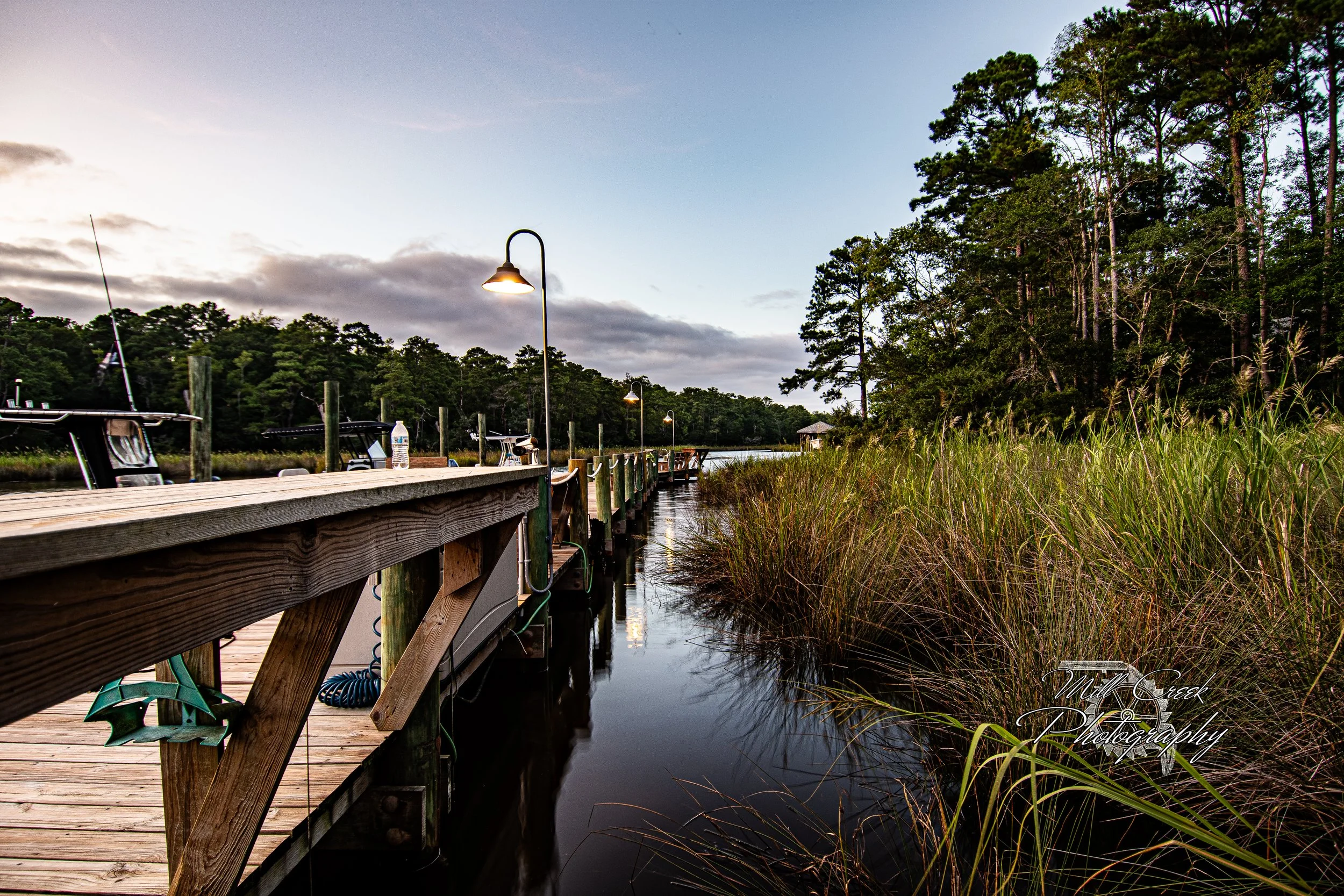"Quiet Dock, Quiet Night"
Long perspective down a working dock lined with skiffs and glowing lamps, bordered by tall marsh grass.