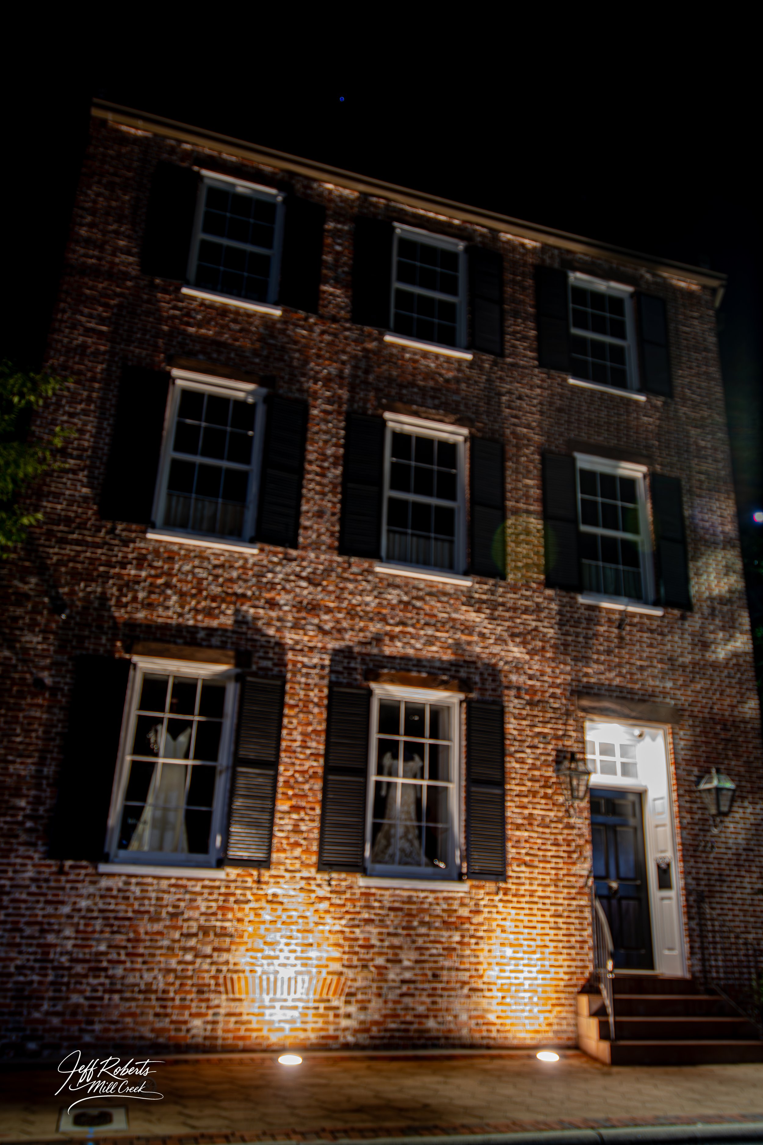 Night view of a brick residential building with illuminated windows and exterior lights.