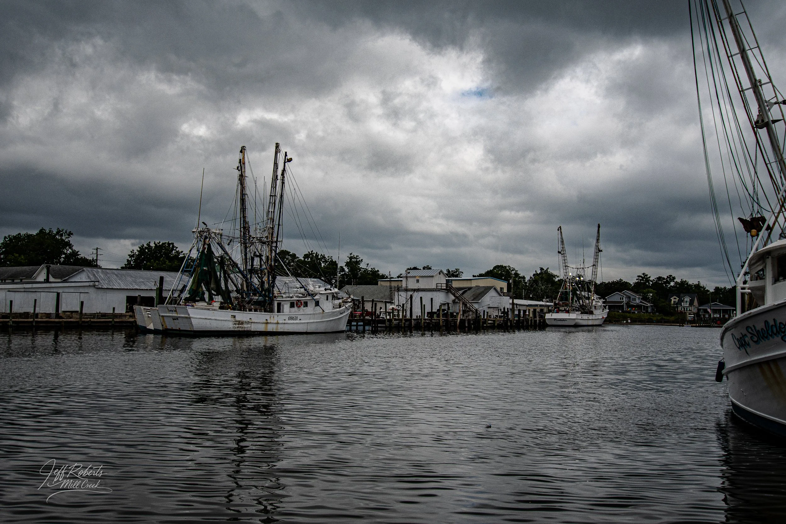 Fishing boats docked along a pier on a cloudy day at Mill Creek.