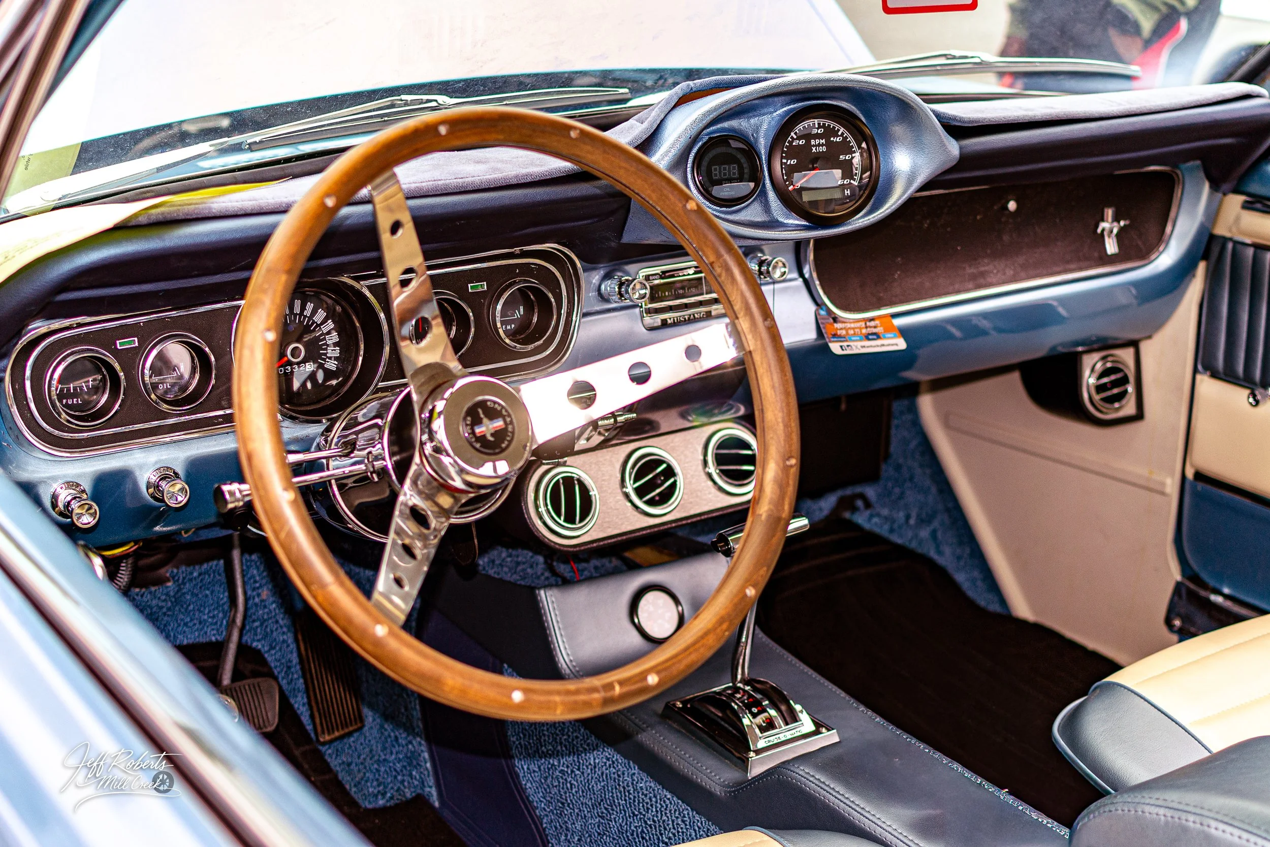 Interior of a vintage Ford Mustang car showing the dashboard, steering wheel, gauges, and gear shift.