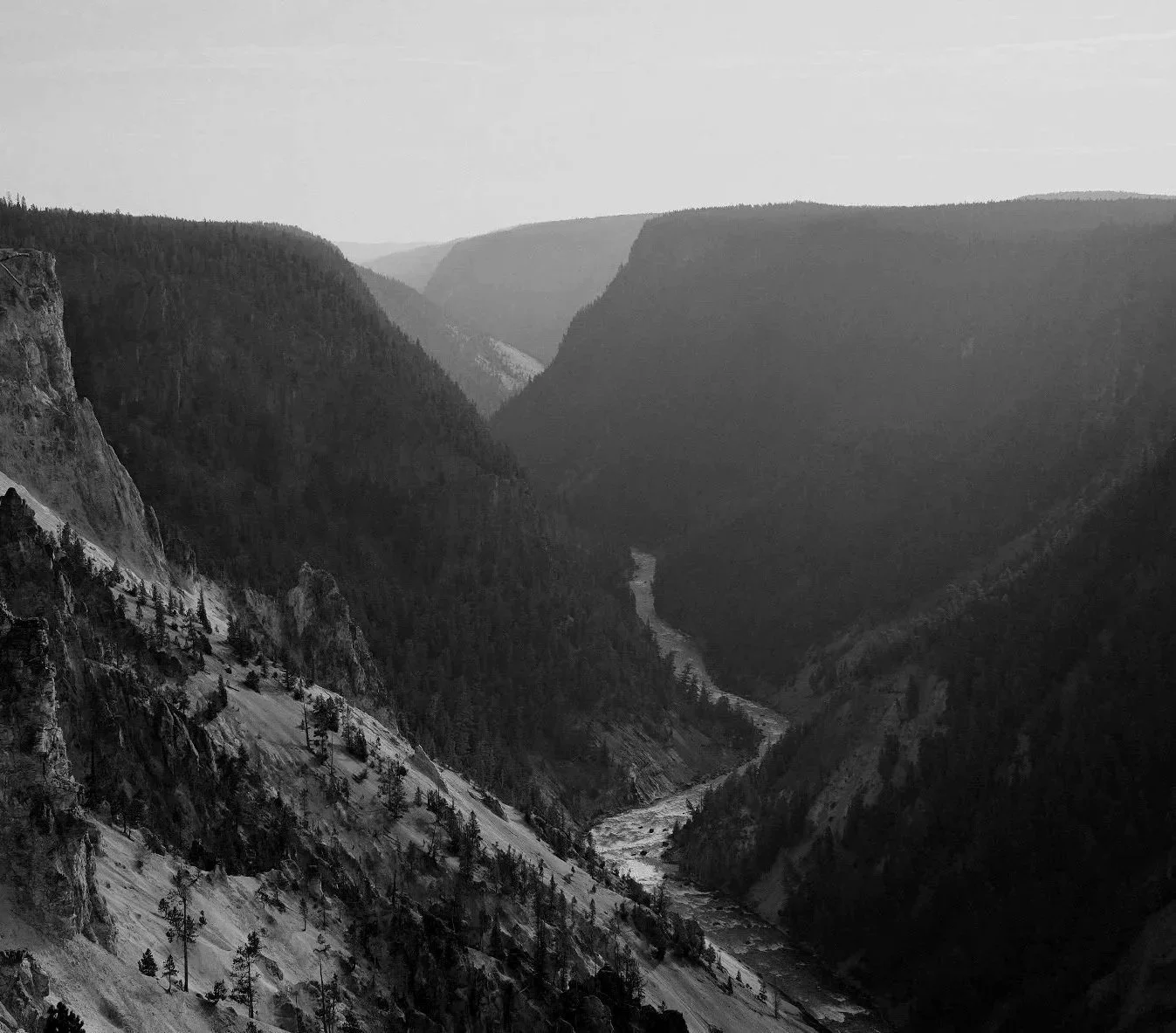 Black and white landscape of a winding river through a deep mountain valley, symbolizing reflection and mindful exploration.