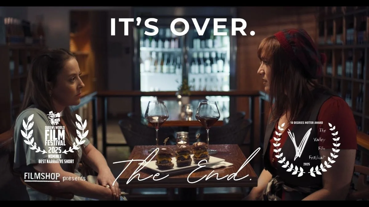 Two women sit across from each other at a table with wine glasses and hamburgers in a cozy restaurant. Overlaid text reads 'IT'S OVER.' and 'The End' at the bottom.