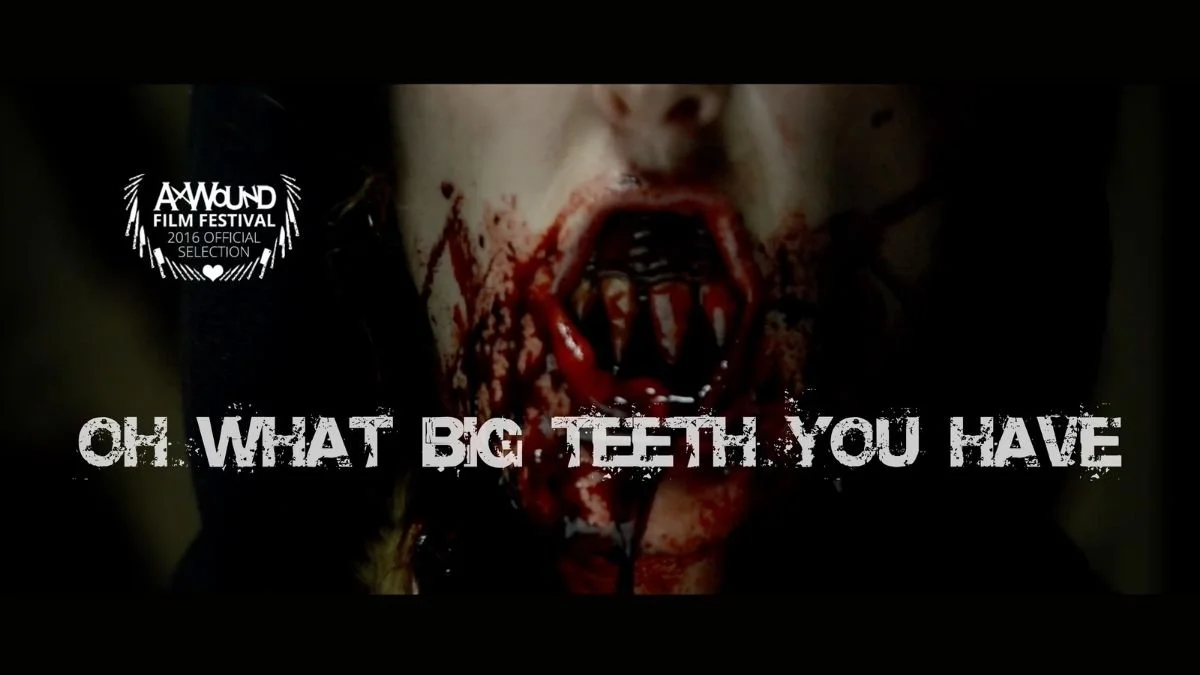 Close-up of a person's face with blood and makeup resembling large, sharp teeth in their mouth, with the caption "Oh! What big teeth you have." and a film festival logo in the top left corner.