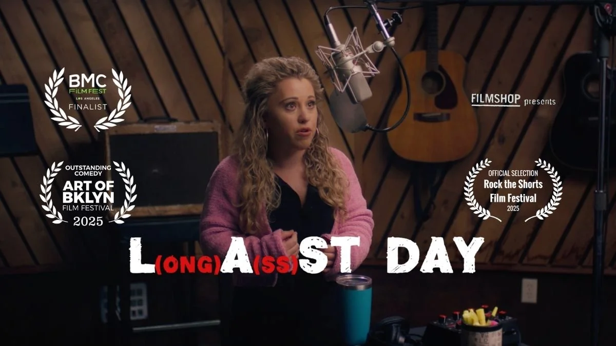 Scene of a woman in a recording studio with wooden paneling, speaking into a microphone, with a guitar hanging on the wall behind her, and awards and festival selections overlaid on the image. The title 'Long (A)ss Last Day' is displayed at the bottom.