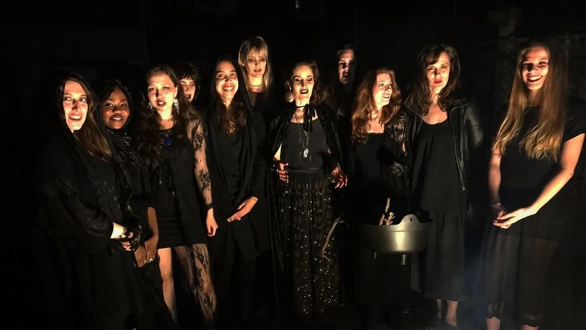 Group of women dressed in black at night, smiling and standing close together.