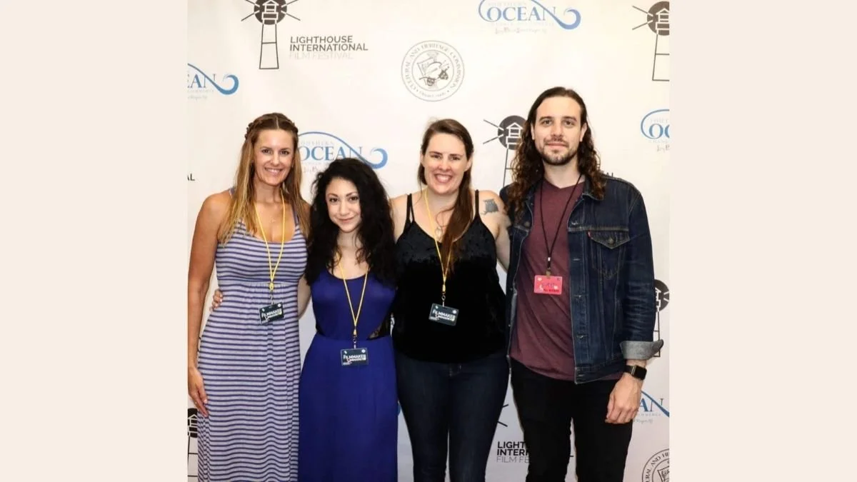 Group of four people smiling, standing in front of a white background with logos for Lighthouse International and Ocean.