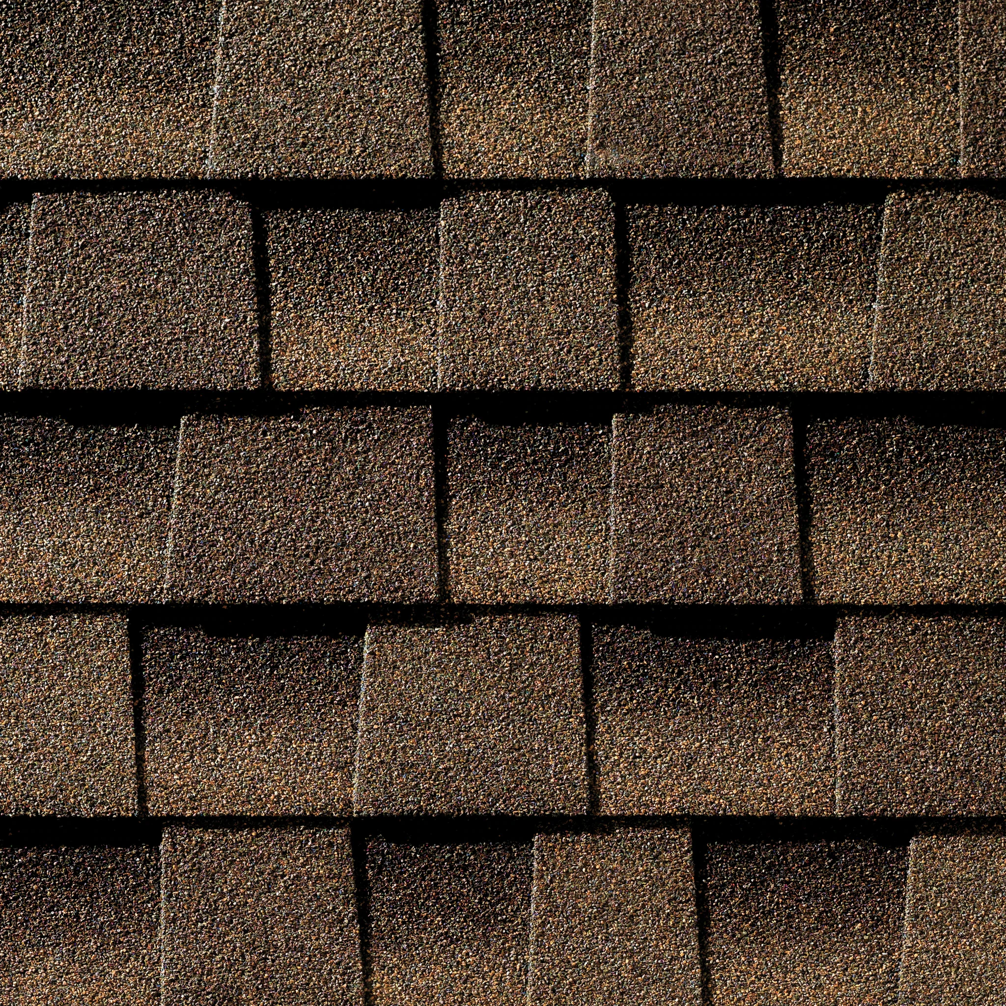 Close-up of brown asphalt roof shingles with black gaps between them.