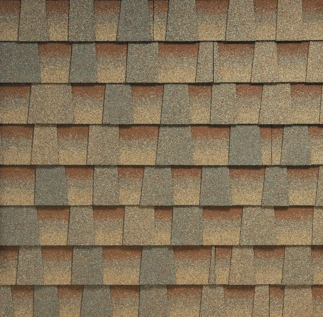 Close-up of a textured roof with overlapping asphalt shingles in various shades of brown and gray.