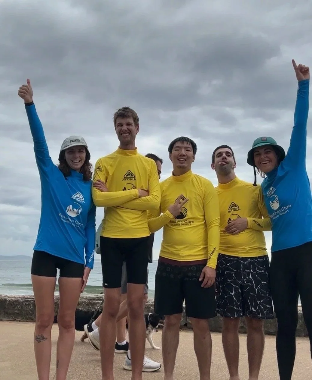 Group of adults in Beaches Care rashvests smiling at the camera.