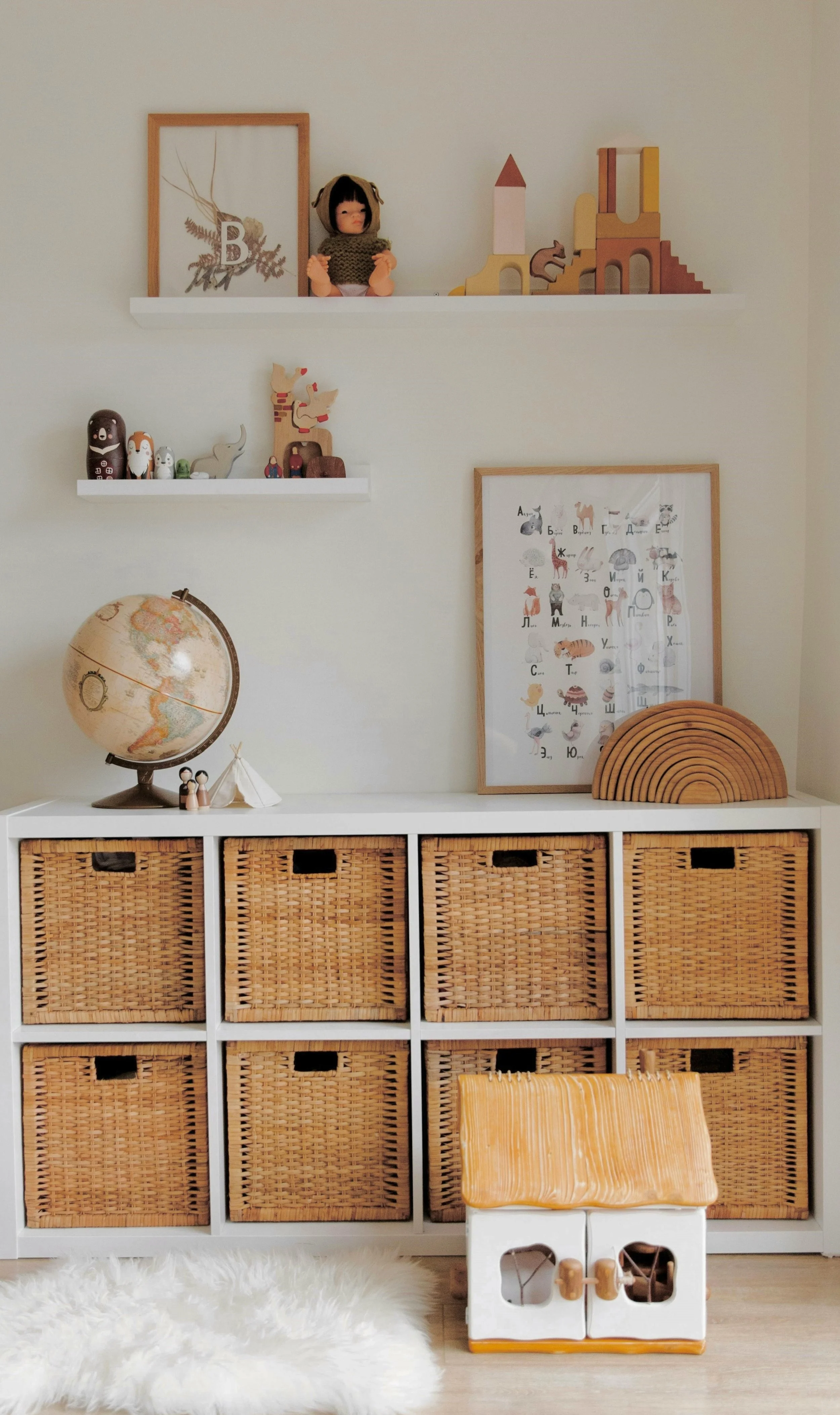 Styled children’s bookshelf with baskets, artwork, and globe as part of a home organization project.